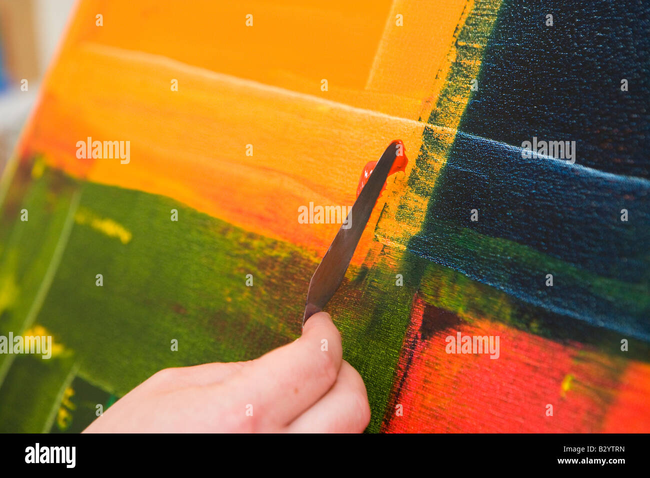 an abstract painting being created by an artist using a knife to apply paint Stock Photo