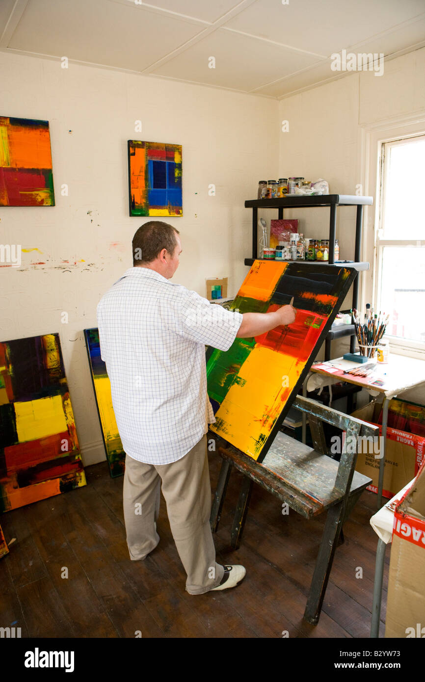 an artist stood at his easel working on an abstract piece of art Stock Photo