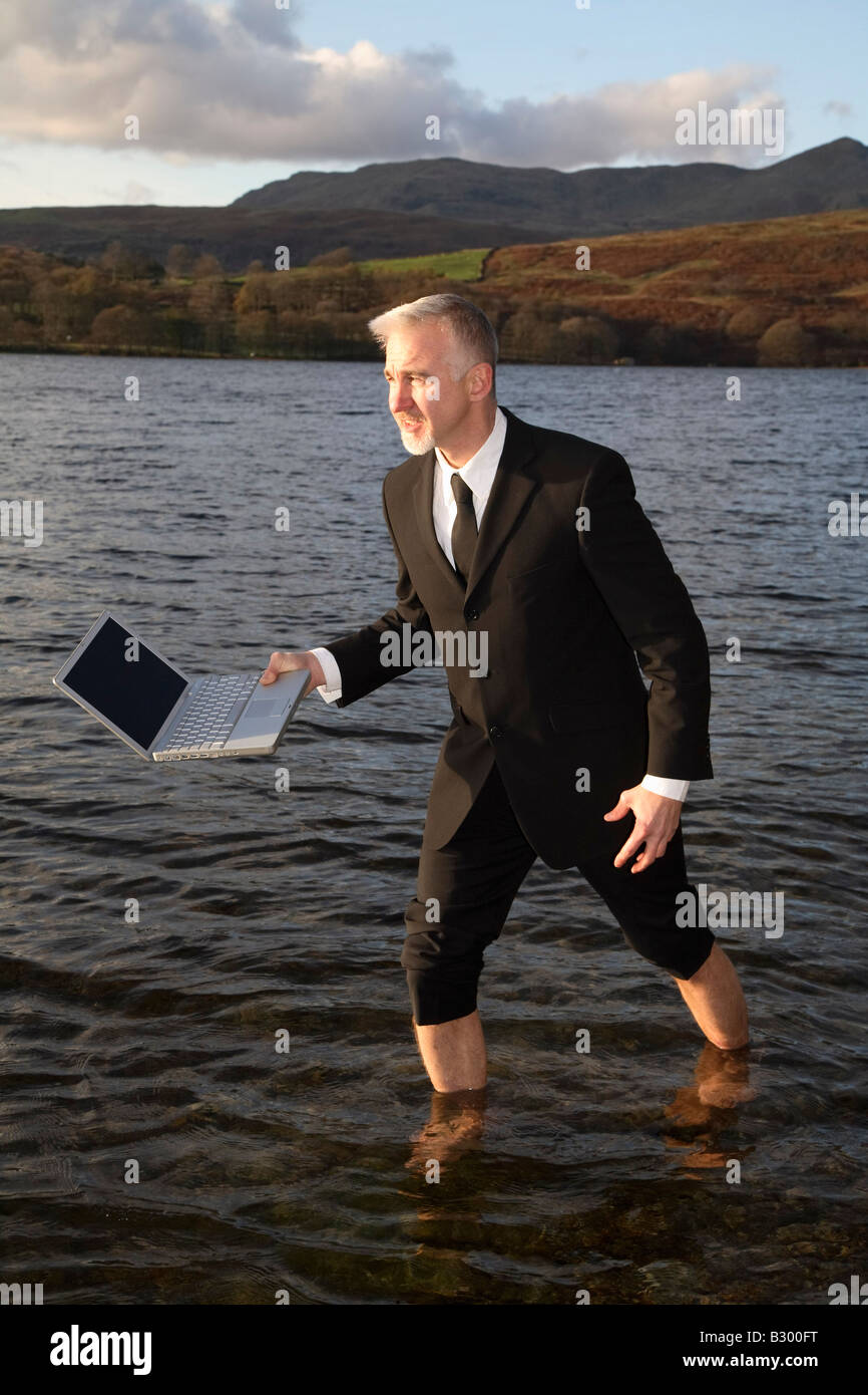 Businessman Walking through Lake with Laptop Computer Stock Photo