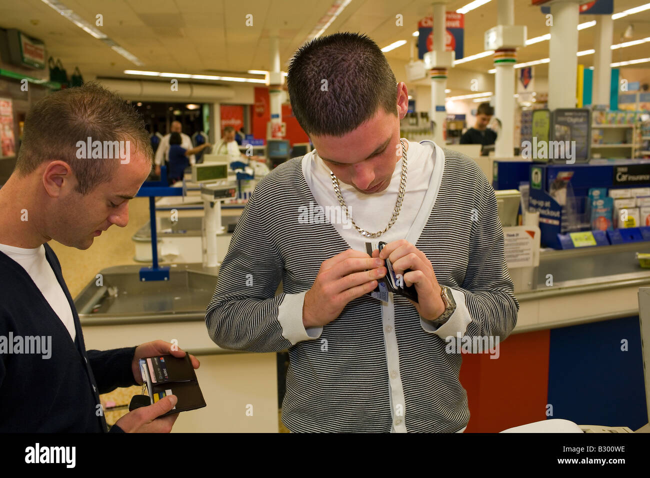 2 lads check their wallets for cash at the Tesco supermarket checkout