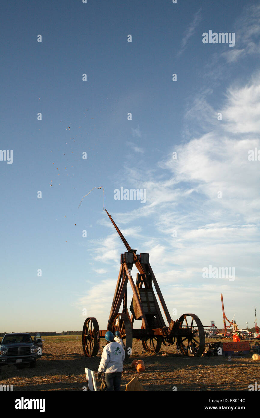 Huge iron wheeled Yankee Siege Trebuchet with pumpkin shattered into thousands of pieces which are blowing back towards machine. Stock Photo