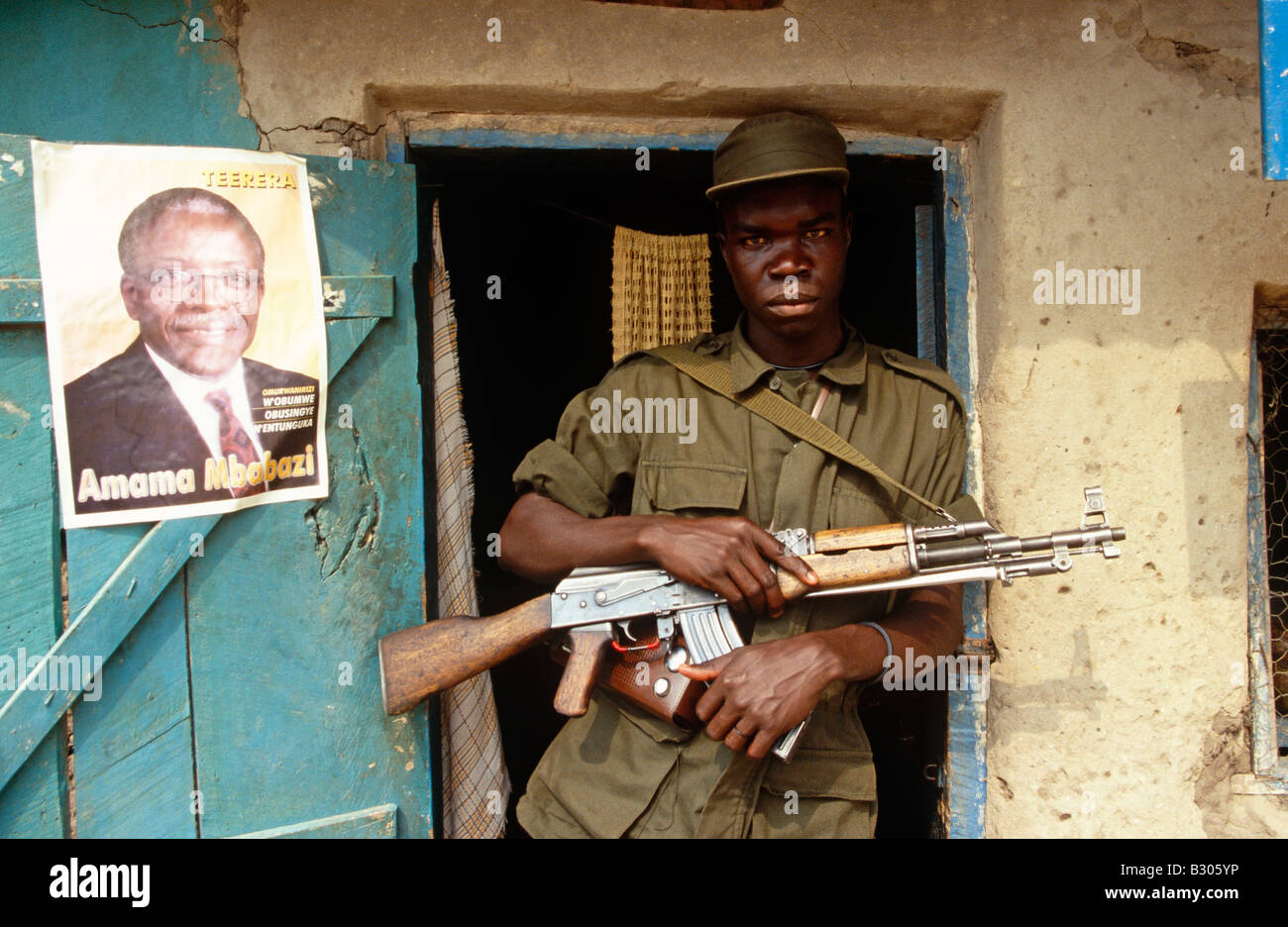 Man with gun standing next to a poster of a politician in Uganda. Stock Photo