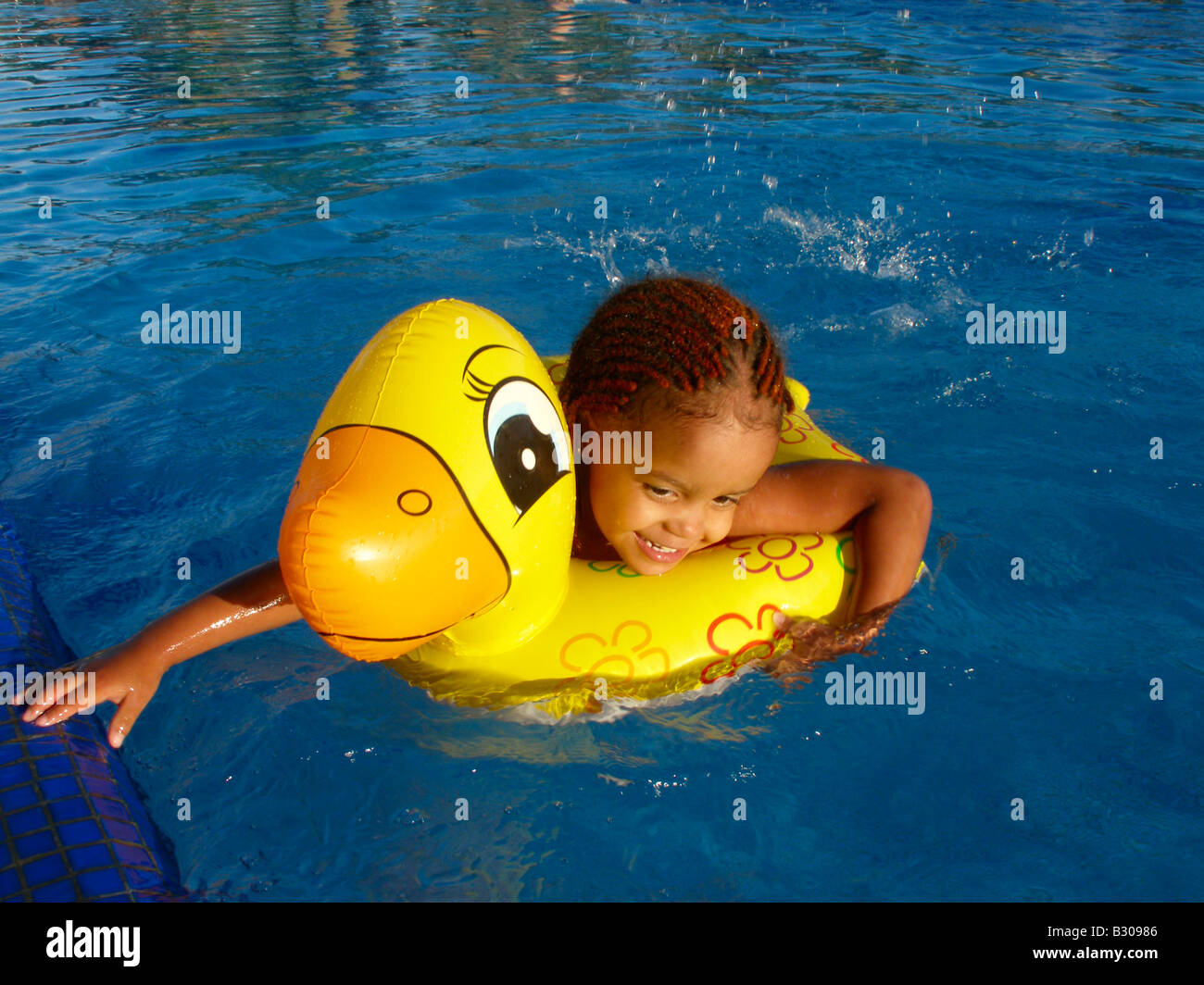 Young girl playing with her yellow duck shaped floater in a swimming