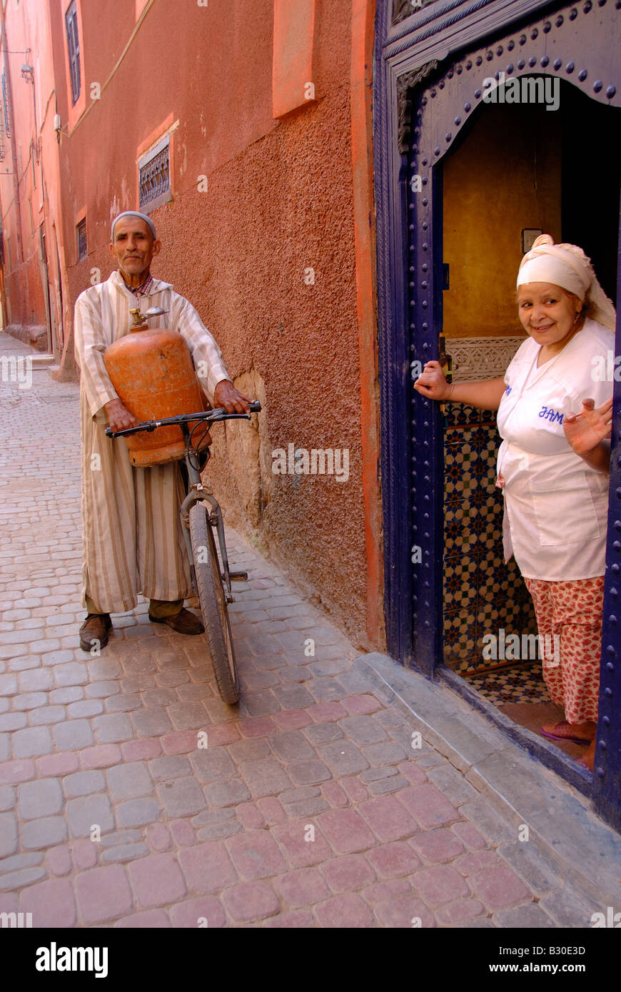 Marrakesh Riad,cook housekeeper taking delivery of gas bottle. Delivered by Bicycle through the narrow streets of Marrakech Stock Photo