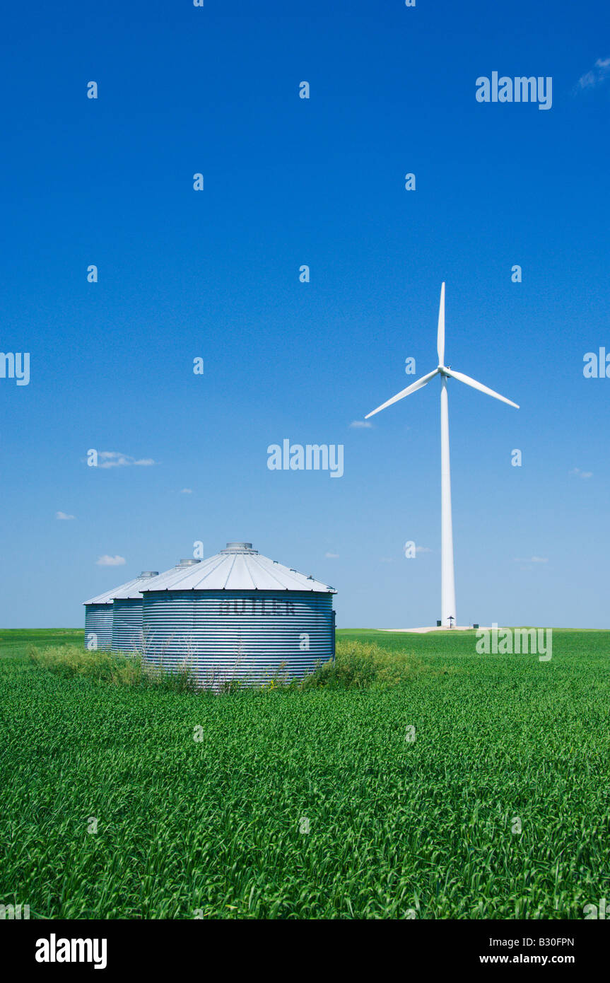 A windmill generating electricity in a field of grain with storage bins in rural North Dakota USA Stock Photo
