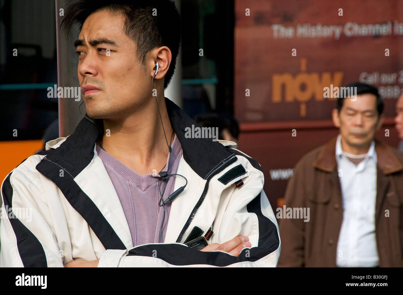 Asian man listening music   while waiting for bus Stock Photo