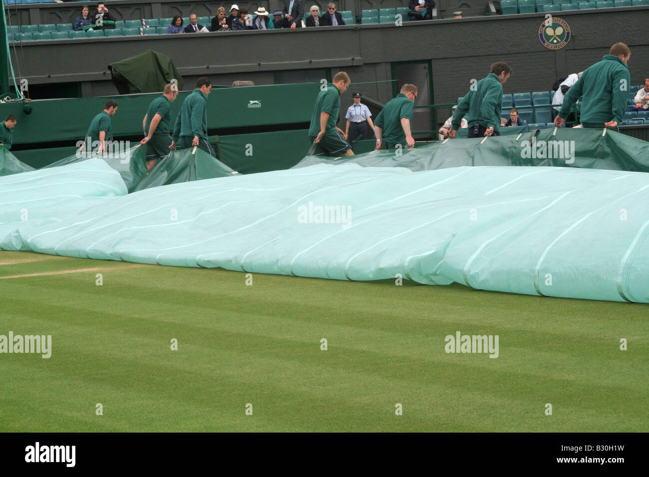 Ground staff remove the cover on centre court after a rain delay at the Wimbledon Tennis