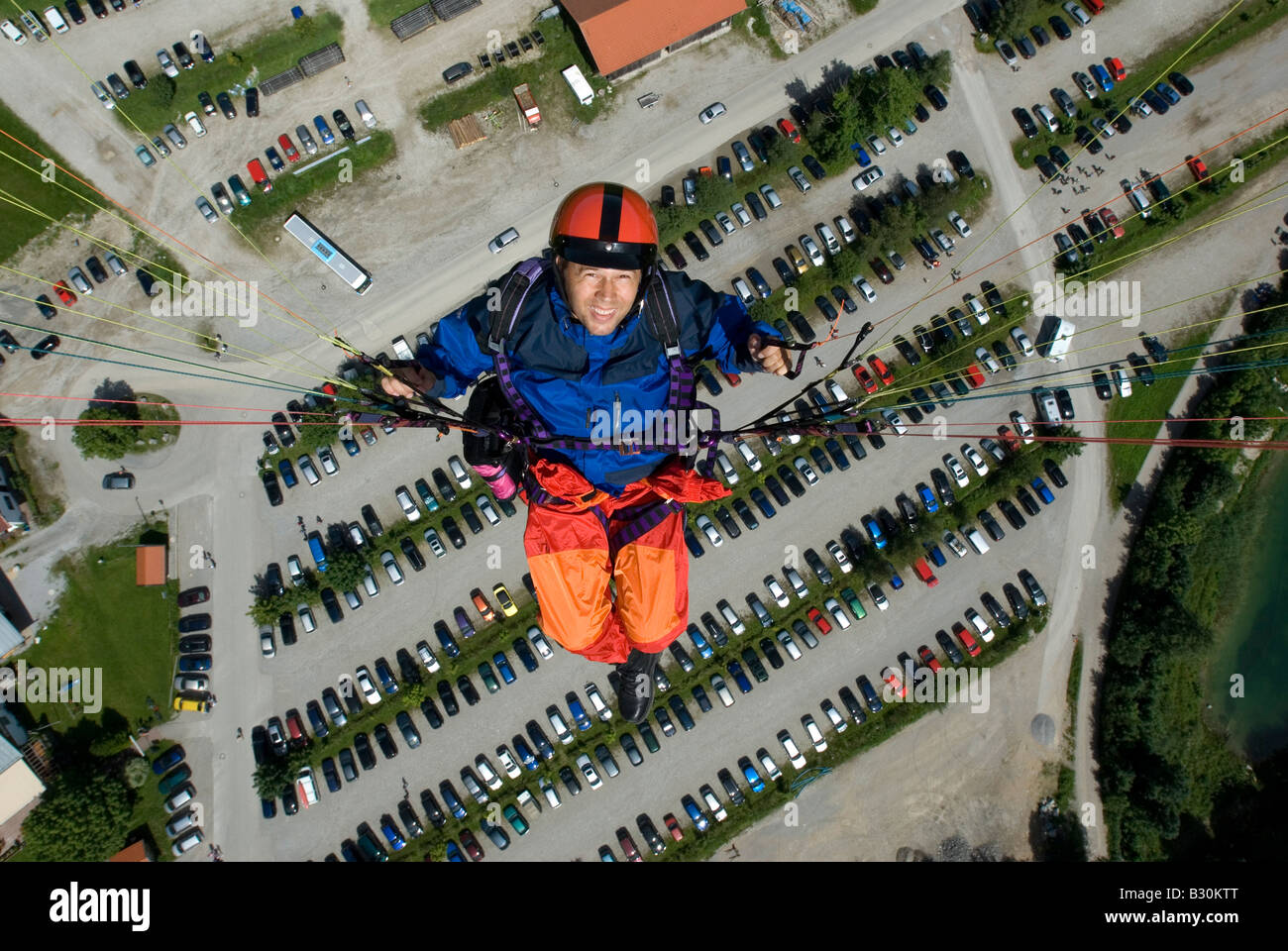 Germany Bavaria Lenggries glider paragliding pilot flying over parking lot of Brauneck cable car ropeway Model Release Nr 0044 Stock Photo