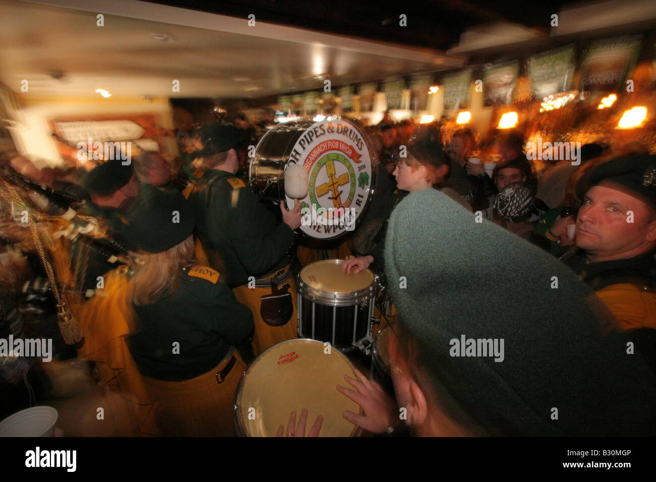 An Irish pipe band plays in a bar/pub to crowds of people on St. Patrick's Day Stock Photo