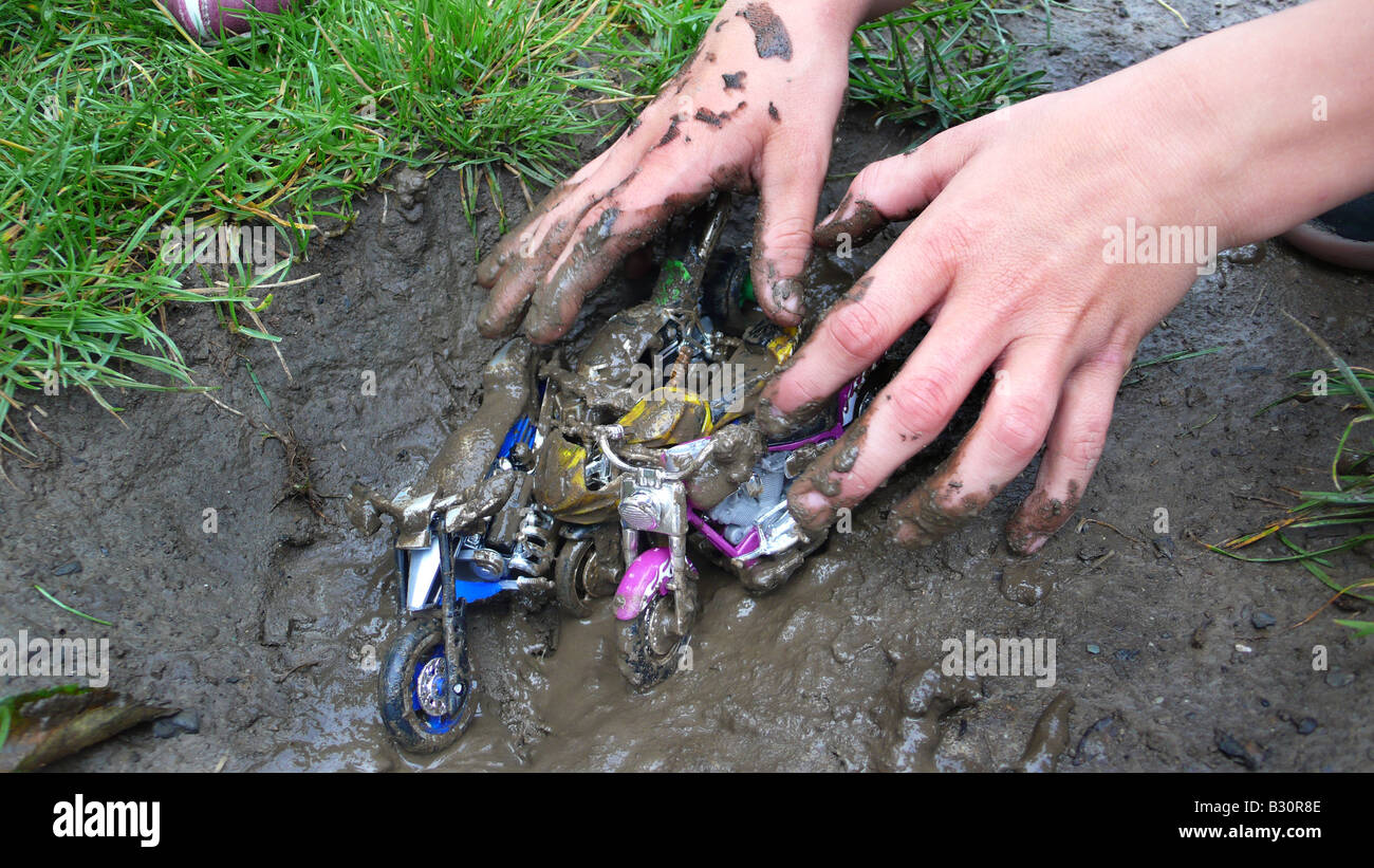 child playing with motor bike toys in mud Stock Photo