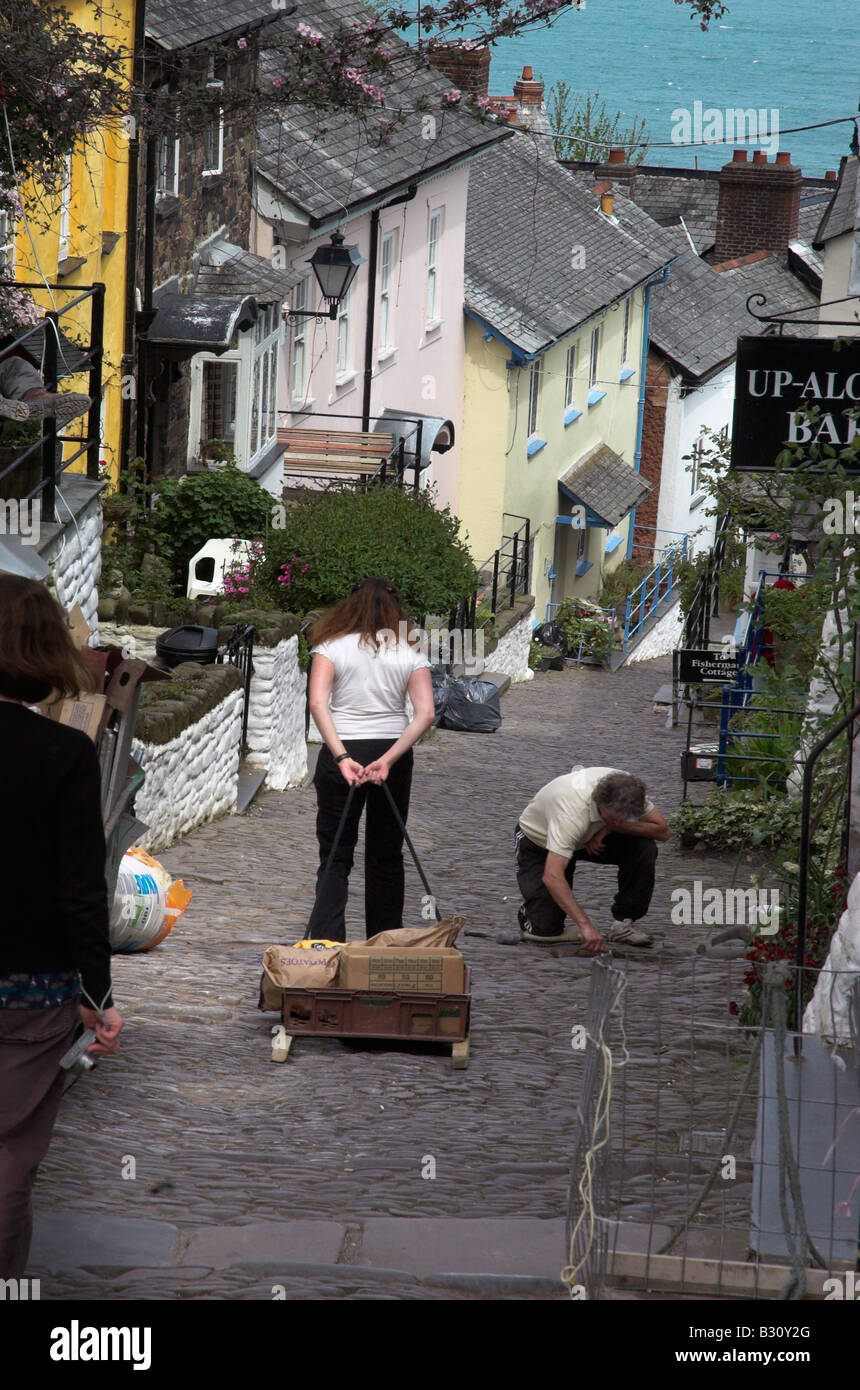 A womn dragging a wooden sled of shopping down the street in Clovelly in Devon Stock Photo