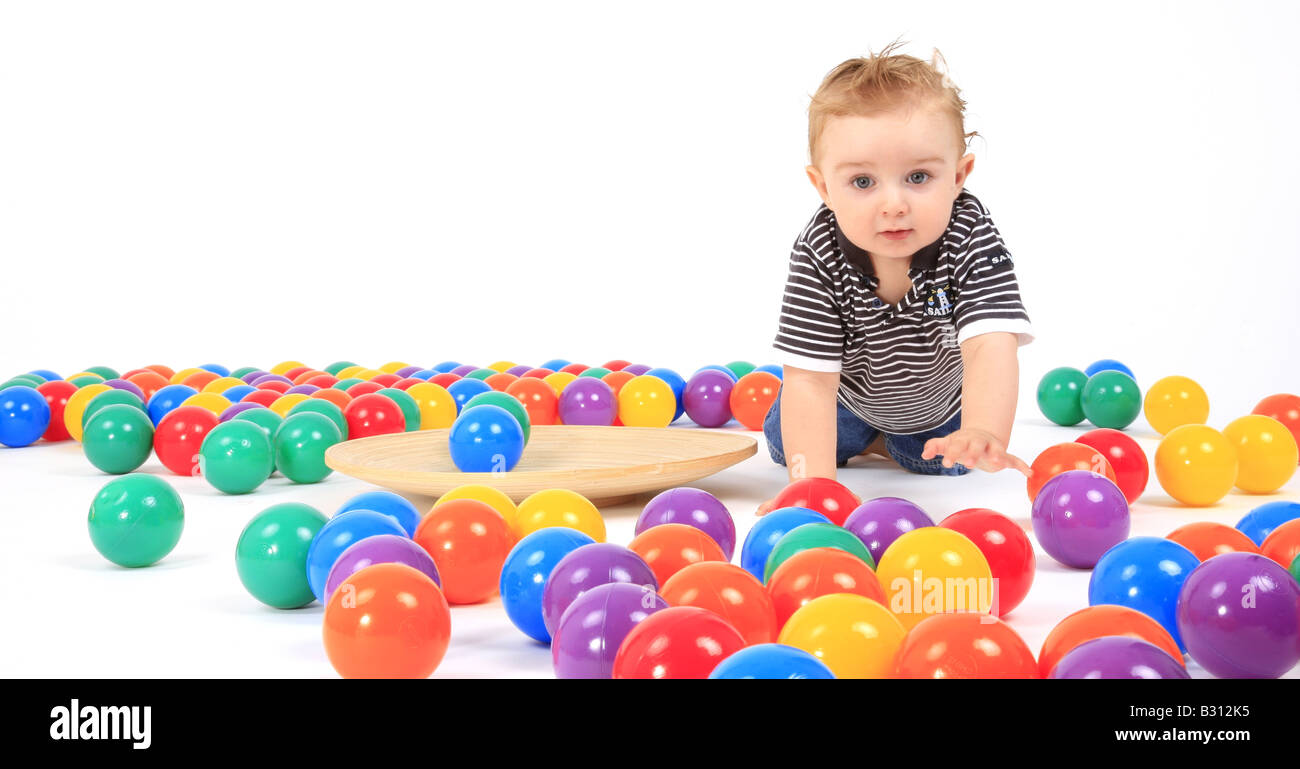 small boy crawling between coloured balls Stock Photo