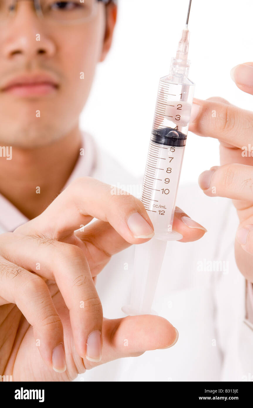 A young asian doctor flicks a syringe to get rid of air bubbles Stock