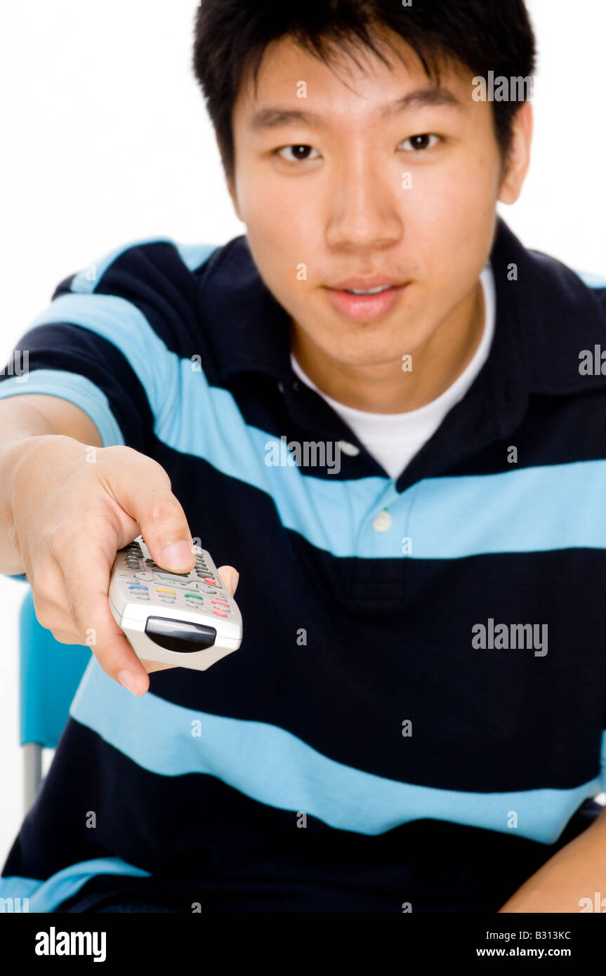 A young man points remote control at the tv (focus on remote) Stock Photo
