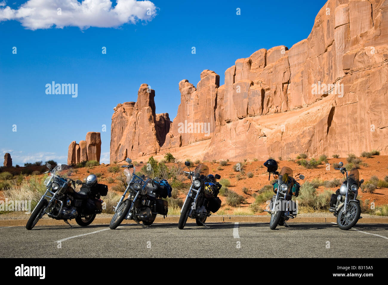 Landscape format colour picture of row of five motorcycles parked up with mountain range behind at Arches National Park Utah USA Stock Photo