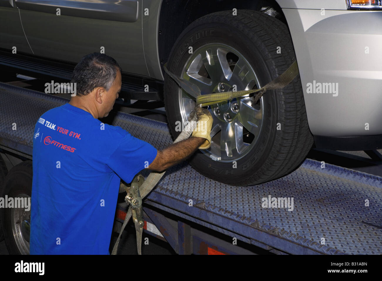 Man securing wheel with ratchet strap Stock Photo - Alamy