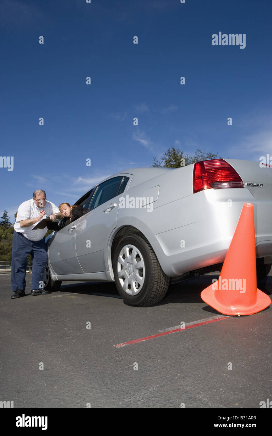 Driving instructor discusses knocked over orange cone with teen Stock Photo