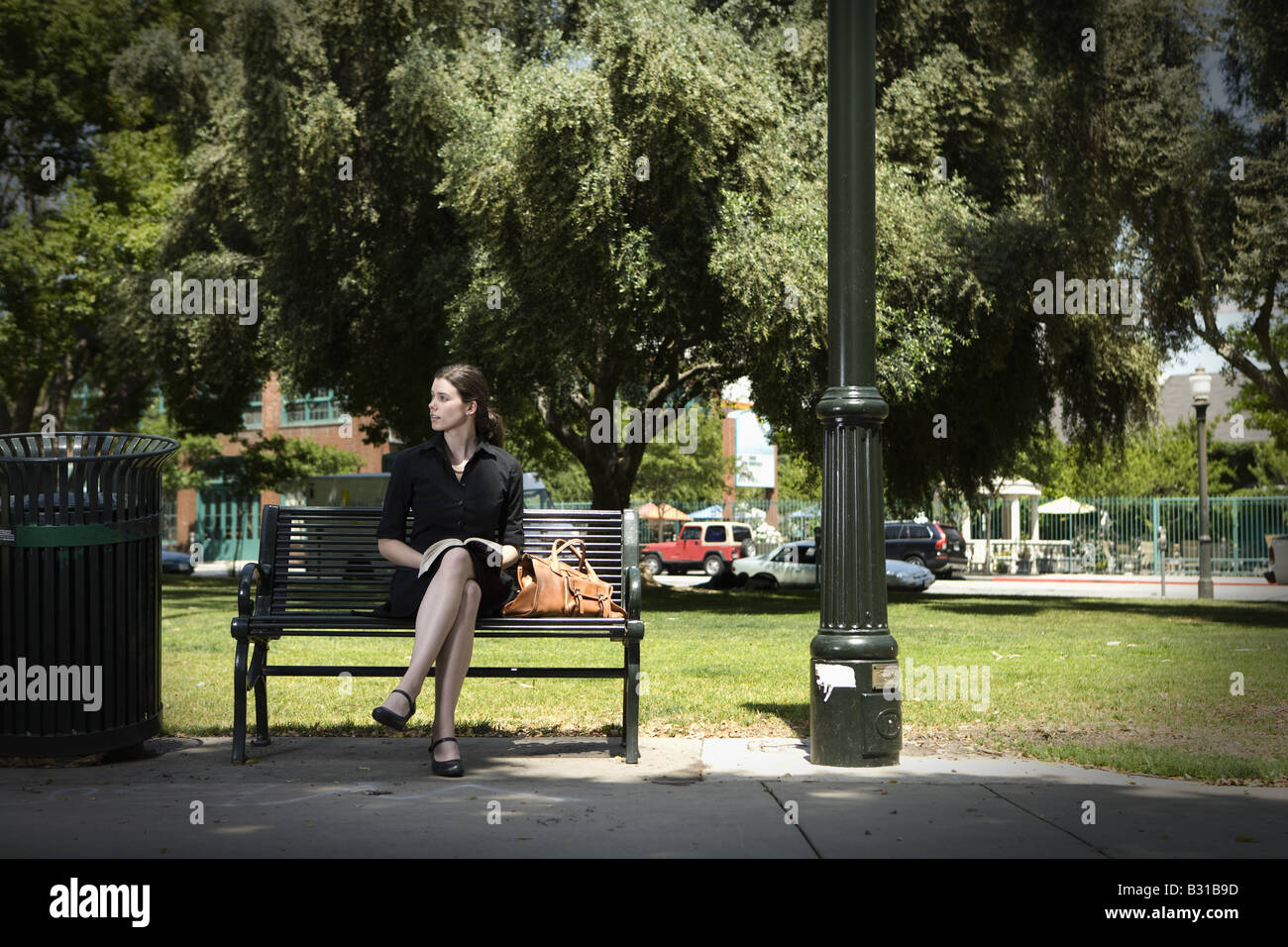 Young woman sitting on park bench with book Stock Photo