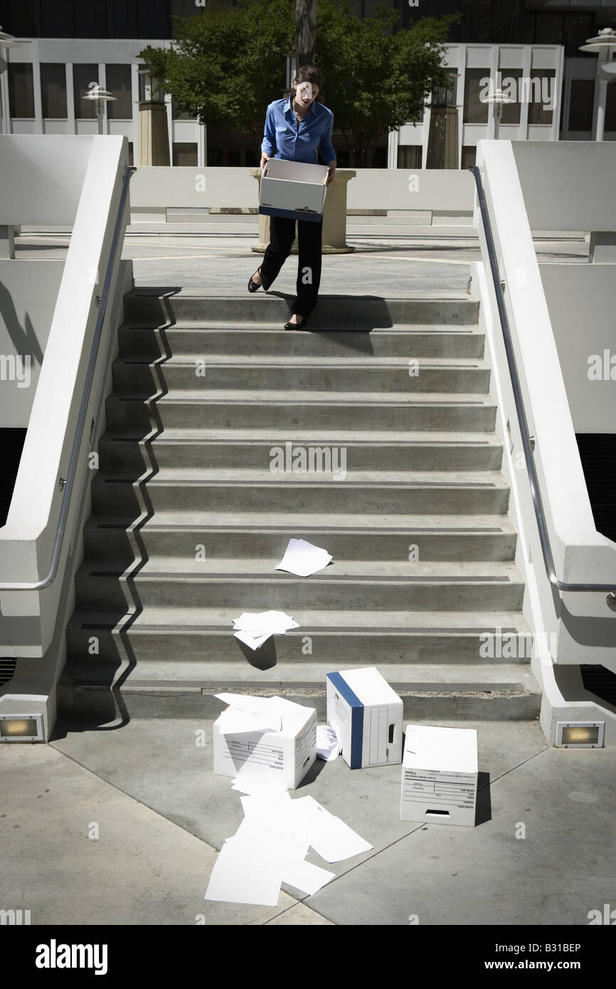 Girl Friday watching boxes of paperwork drop down steps Stock Photo