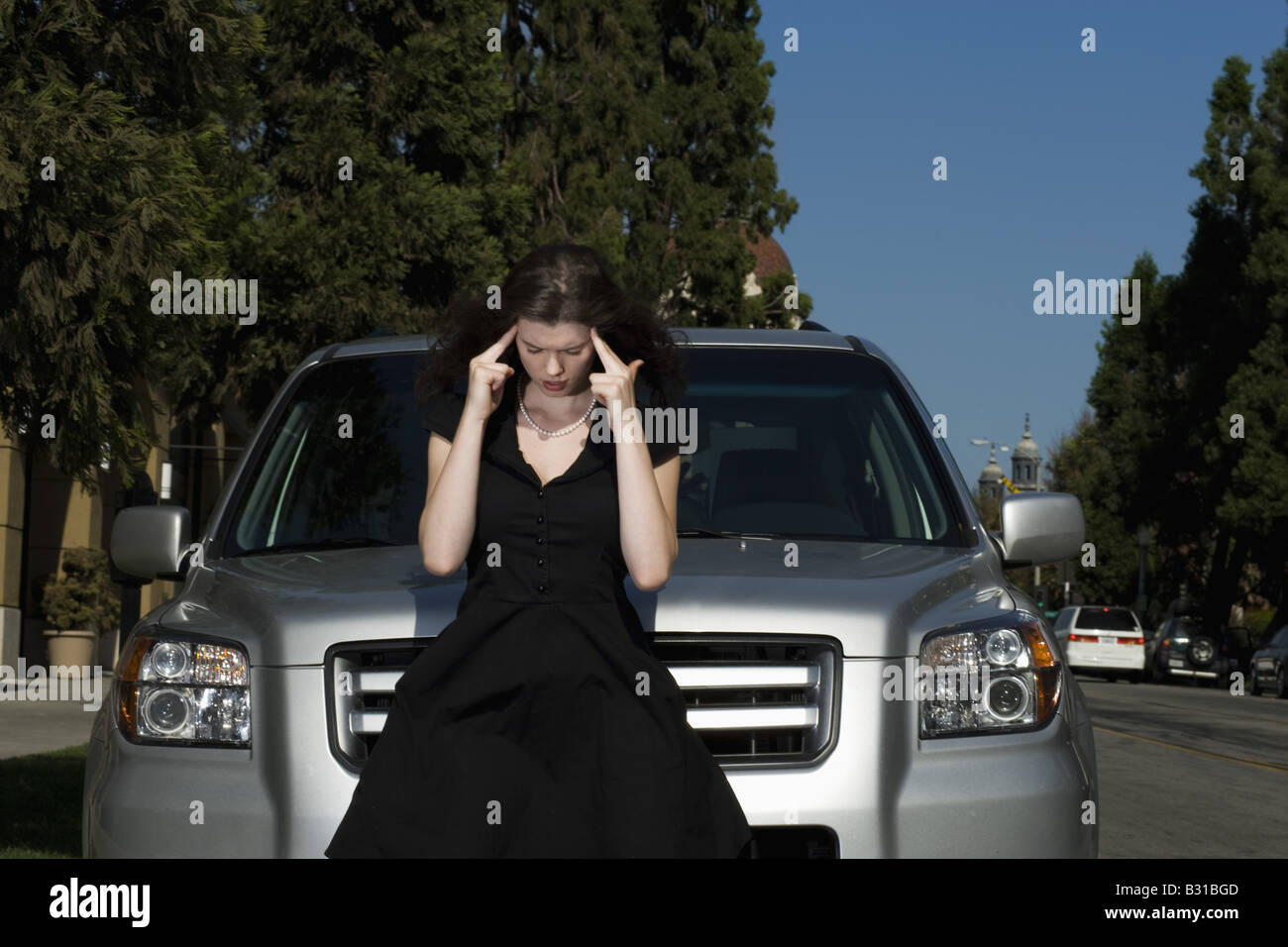 Young woman with headache by Honda Pilot Stock Photo