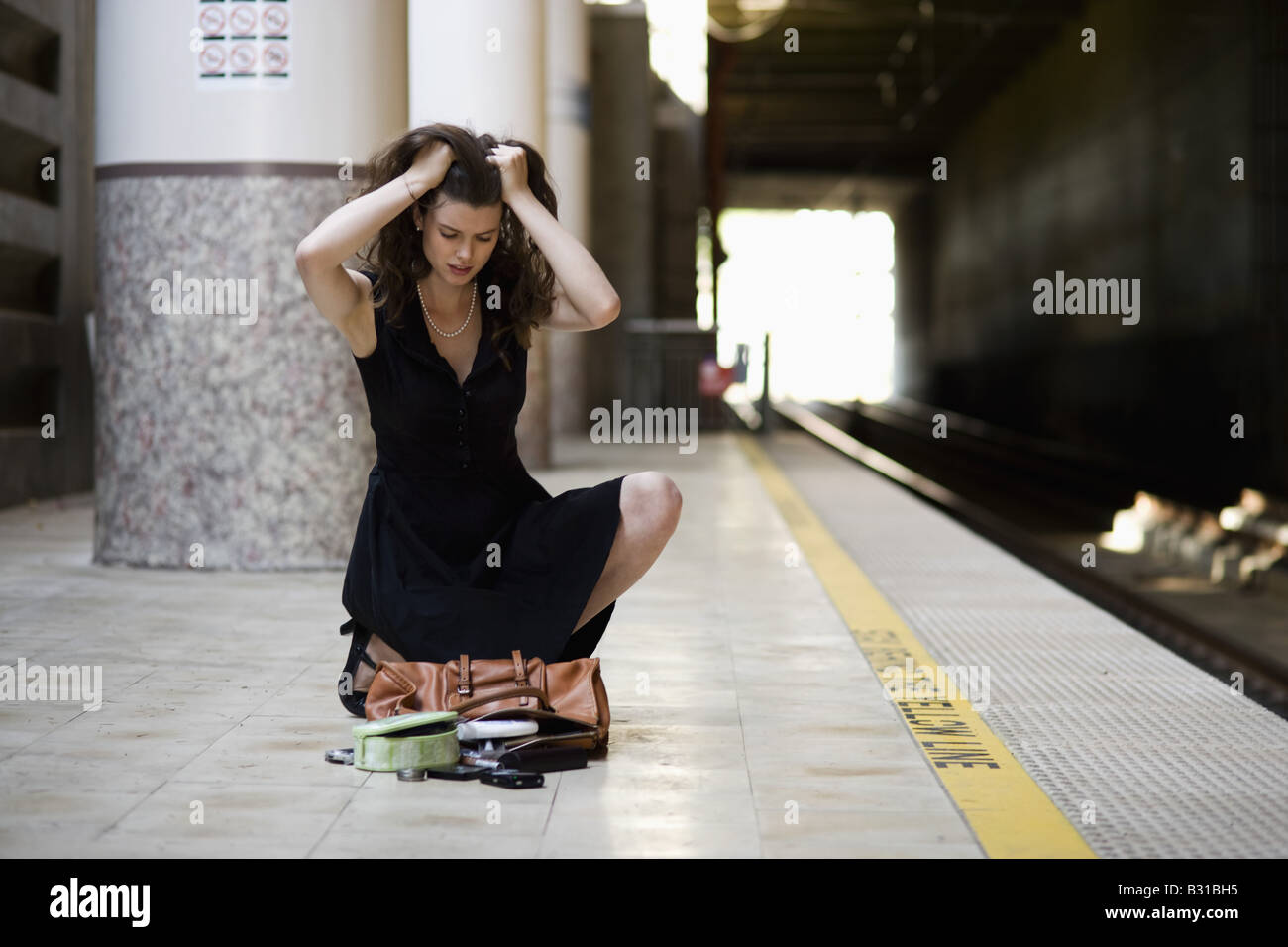 Young woman picking up spilled personal items from the floor Stock Photo