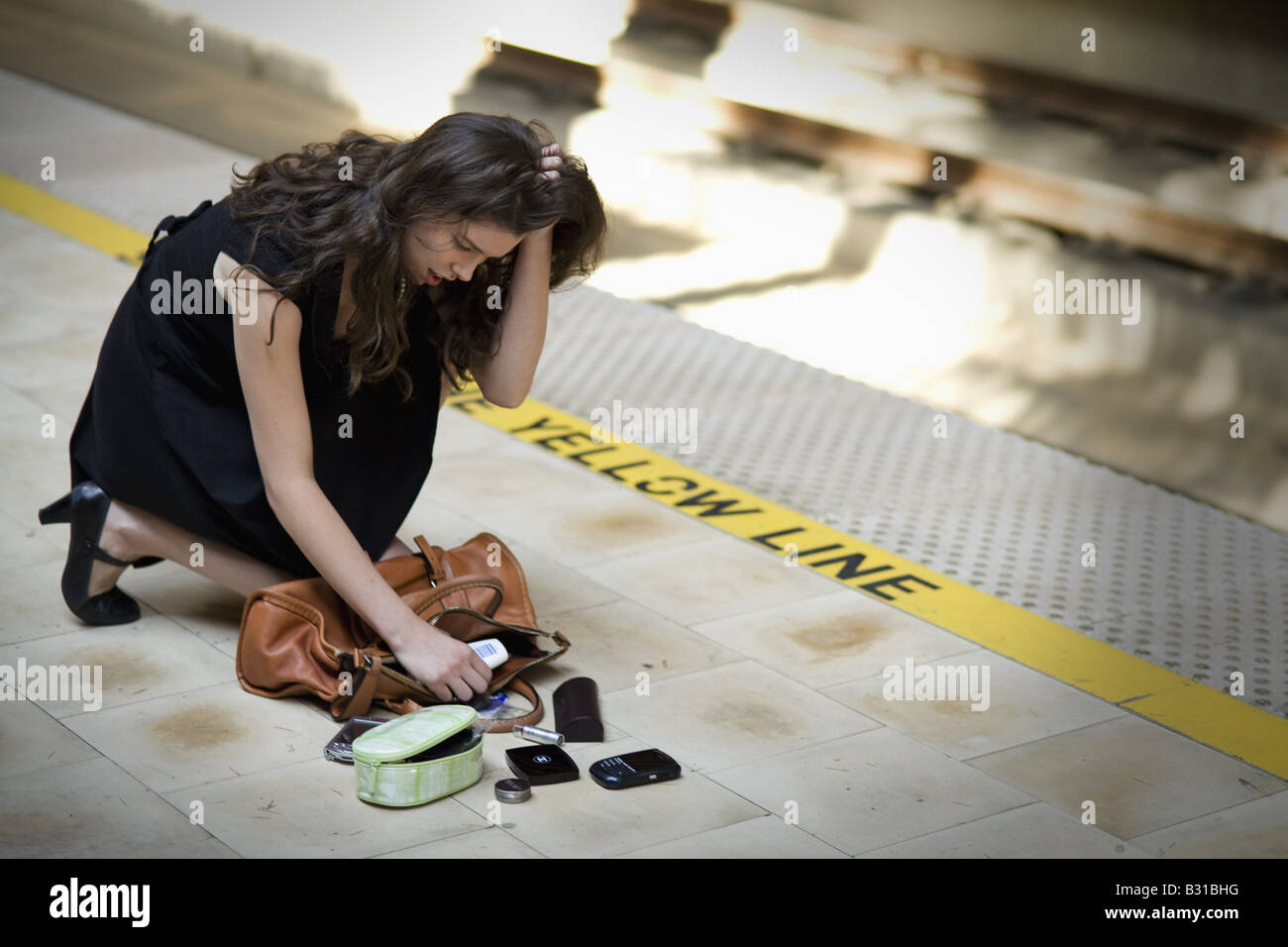 Young woman picking up spilled personal items from the floor Stock