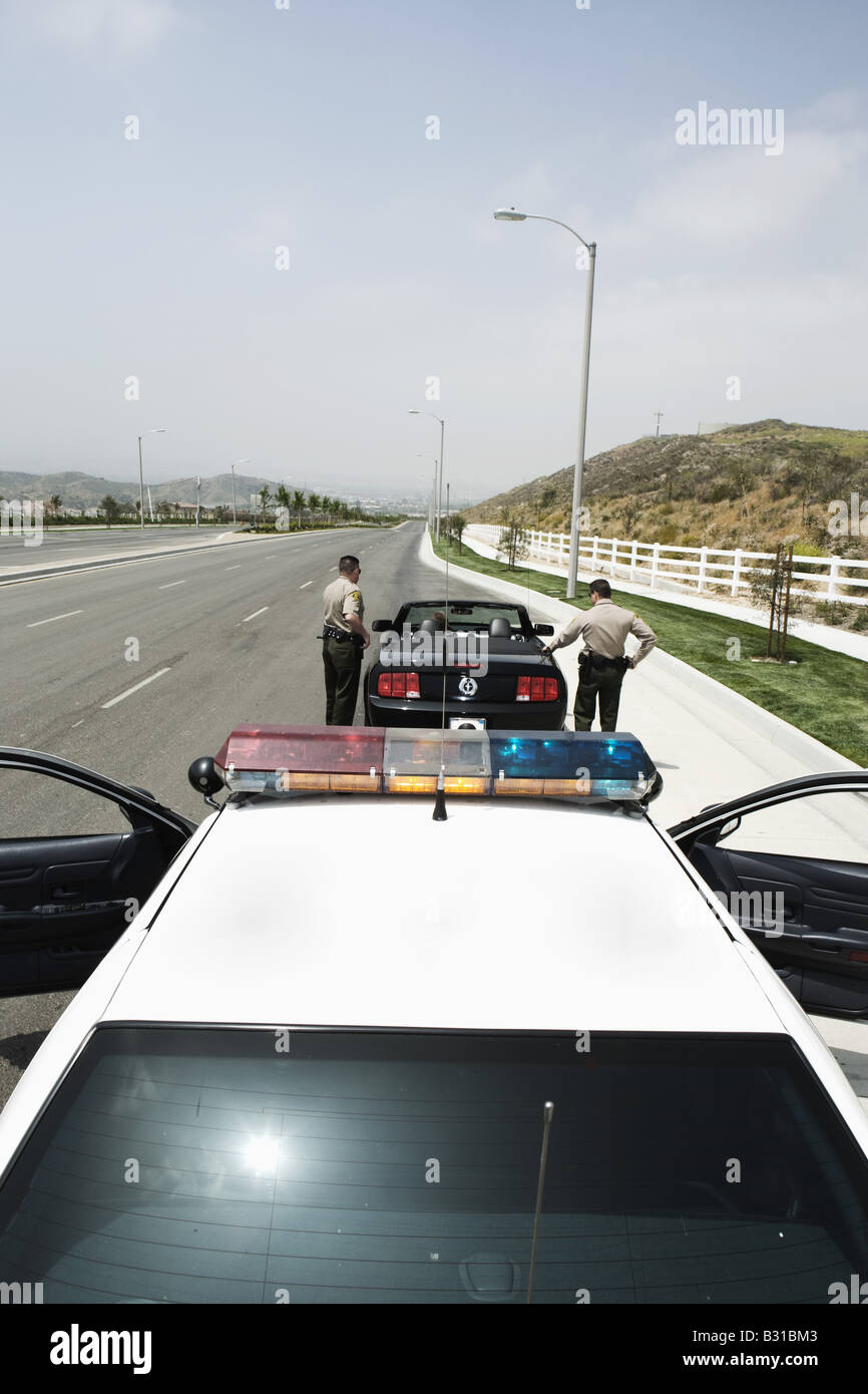 Two police officers approaching man driving Mustang Stock Photo