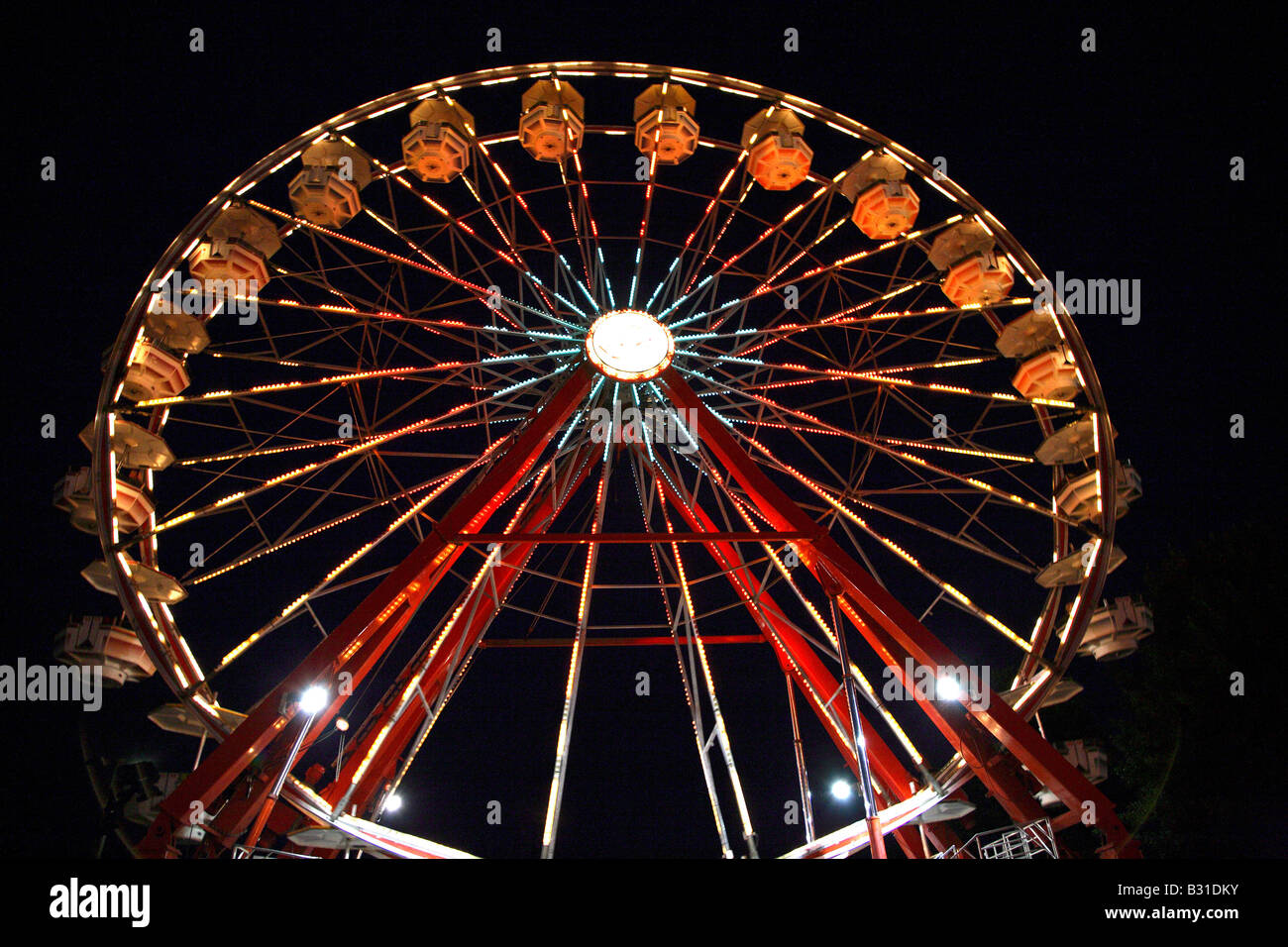 The Big Wheel / Ferris Wheel from directly in front looking up.  All spokes lit and gondolas illuminated from below. Stock Photo