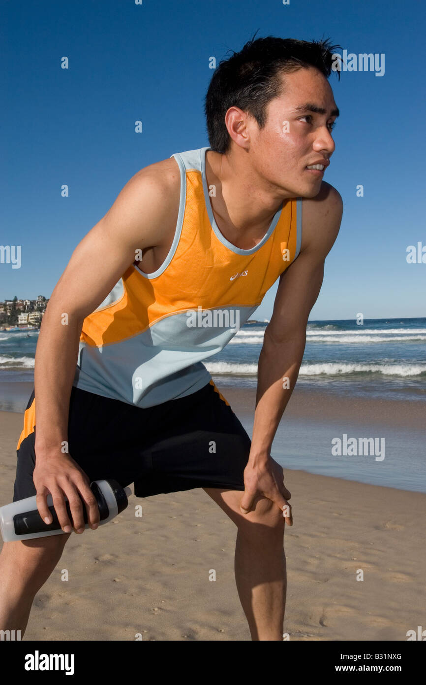 Male Runner Pausing for Breath on Beach Stock Photo