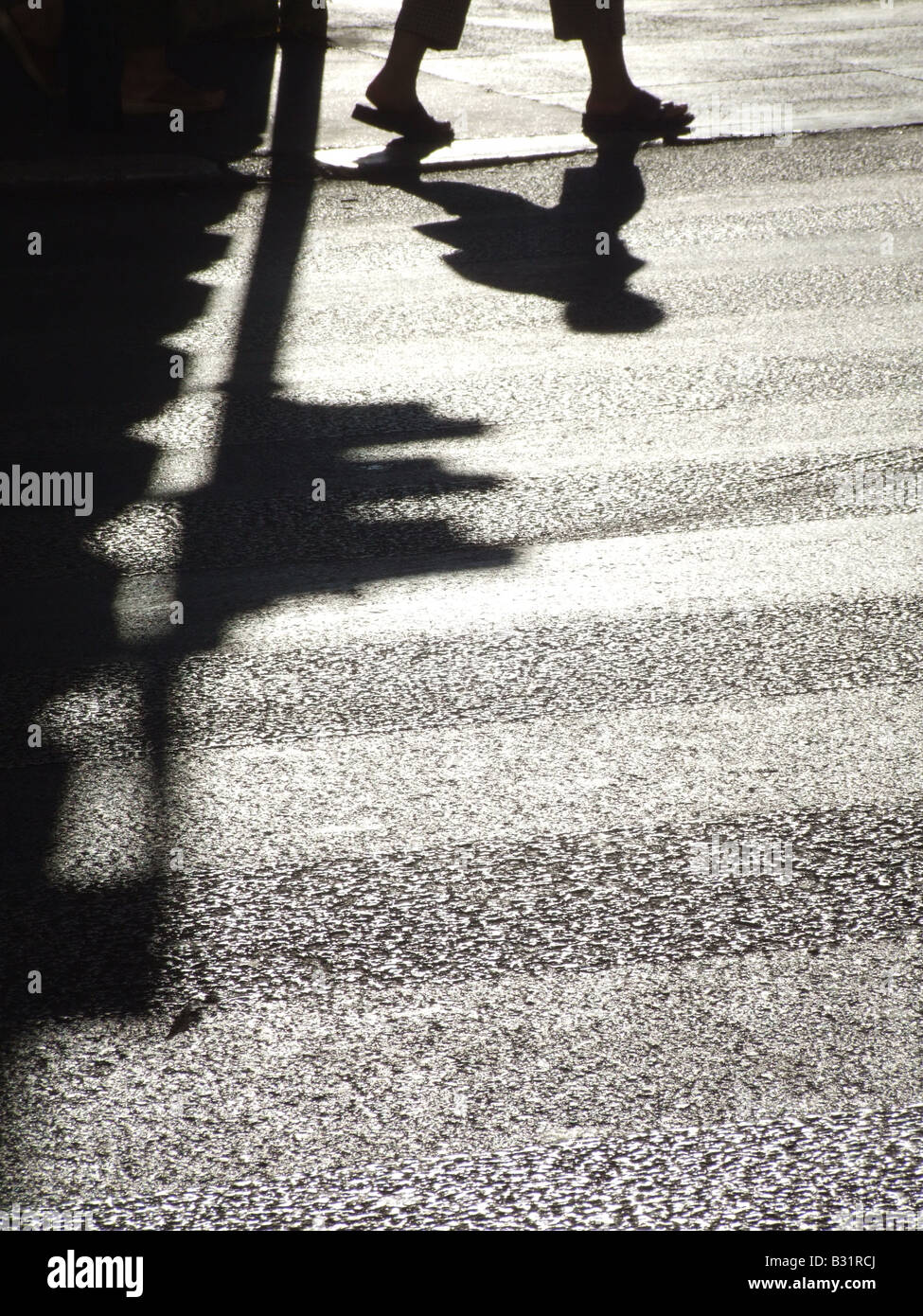 person's dark shadow on road surface in town Stock Photo