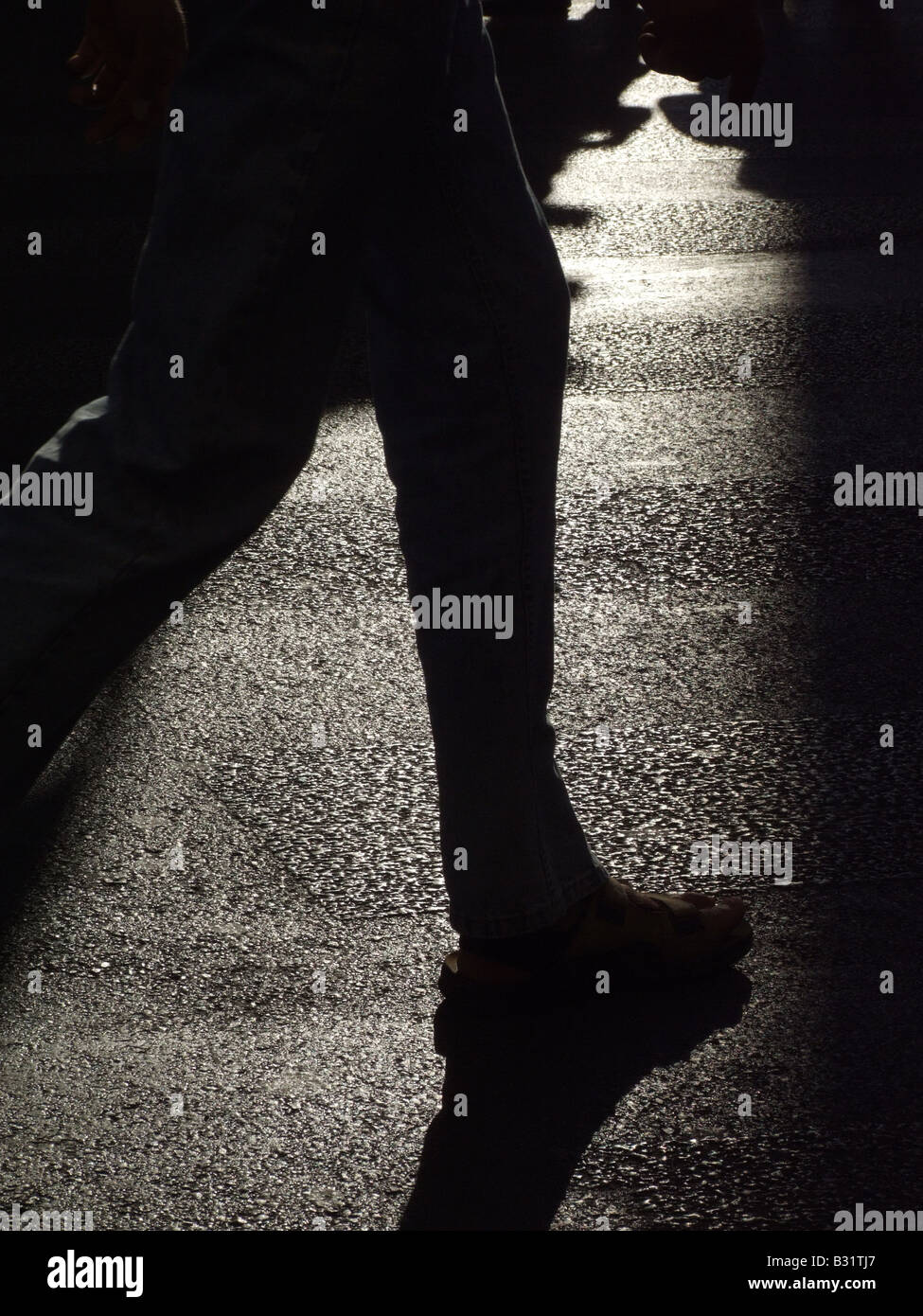 person's dark shadow on road surface in town Stock Photo