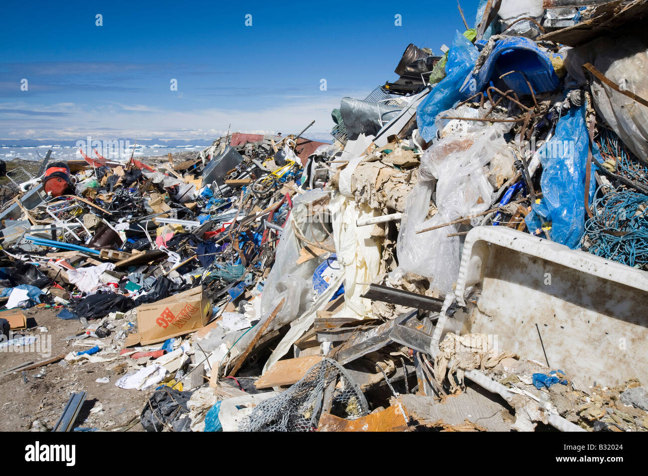 Ilulissat town rubbish dump with icebergs behind, Greenland Stock Photo