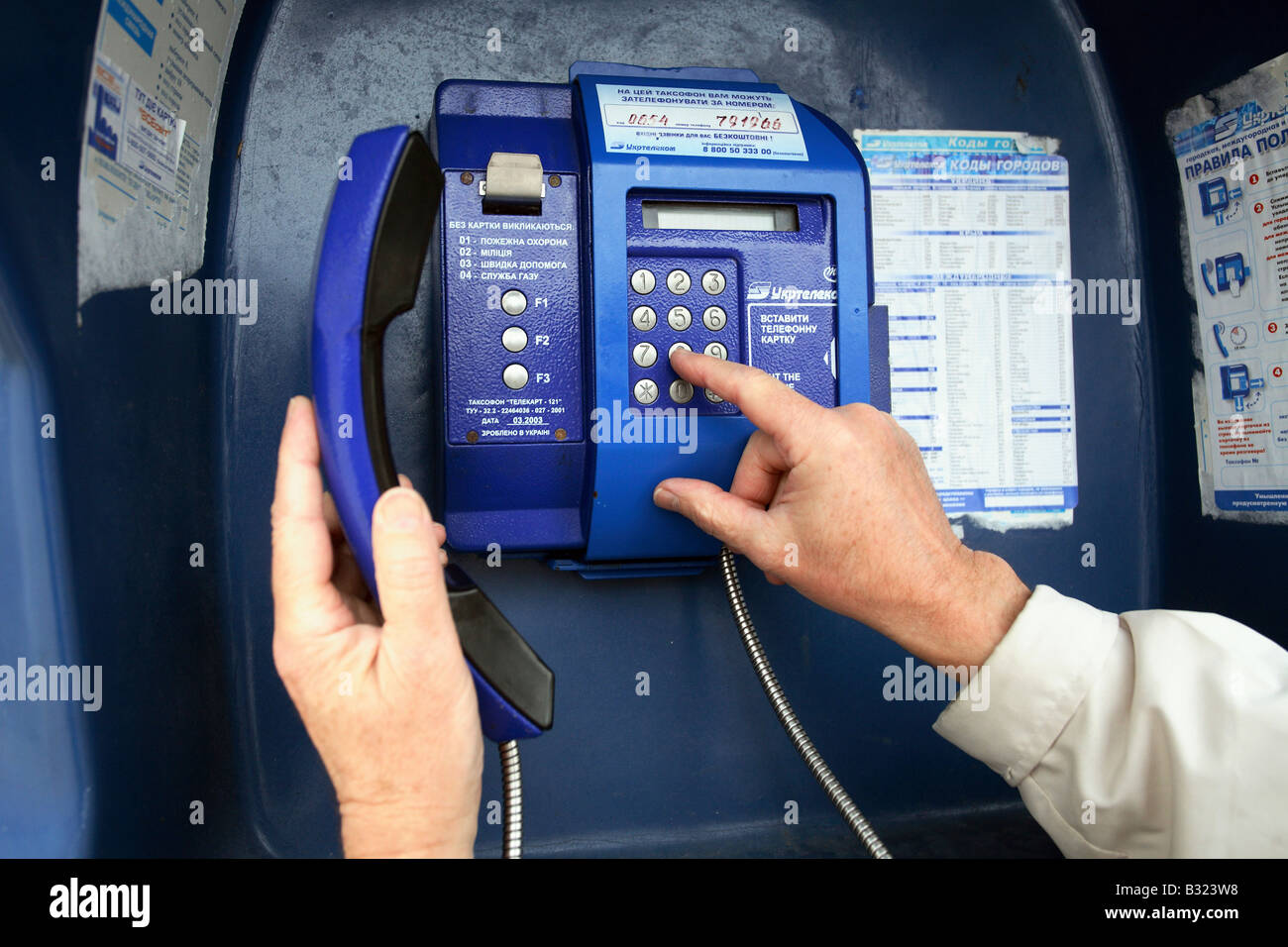 Man dialing a telephone number at a public phone booth, Yalta, Ukraine Stock Photo