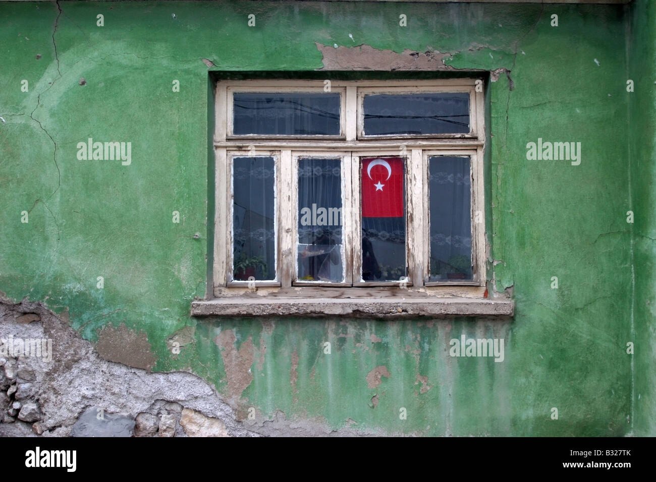 Turkey's flag hang in a window suranded with green old wall Stock Photo