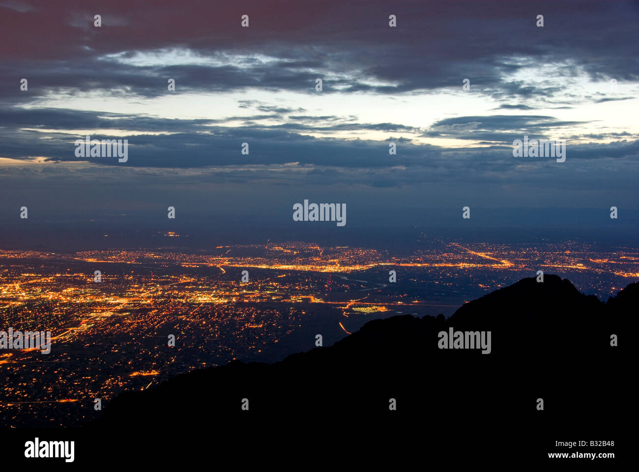 Sandia mountain ridges silhouetted against nighttime Albuquerque city lights Stock Photo