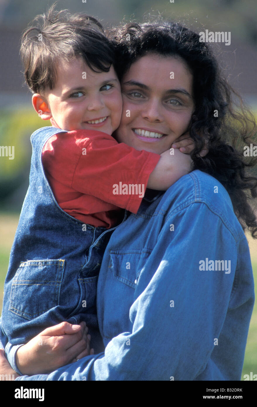 outdoor portrait dark haired mother cuddling her little boy Stock Photo