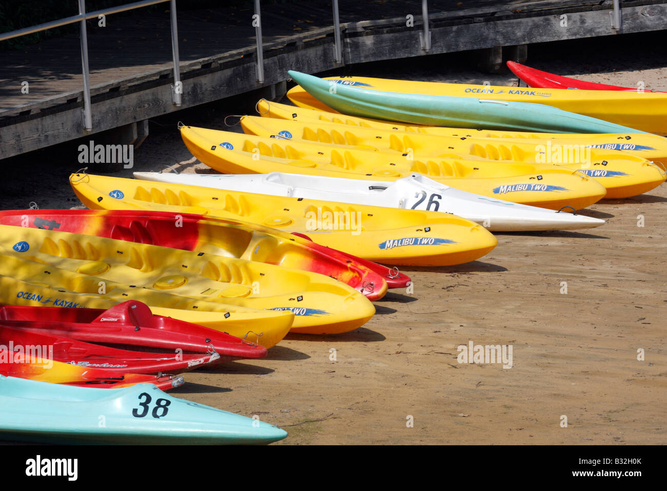 Brightly coloured kayaks along beach Stock Photo