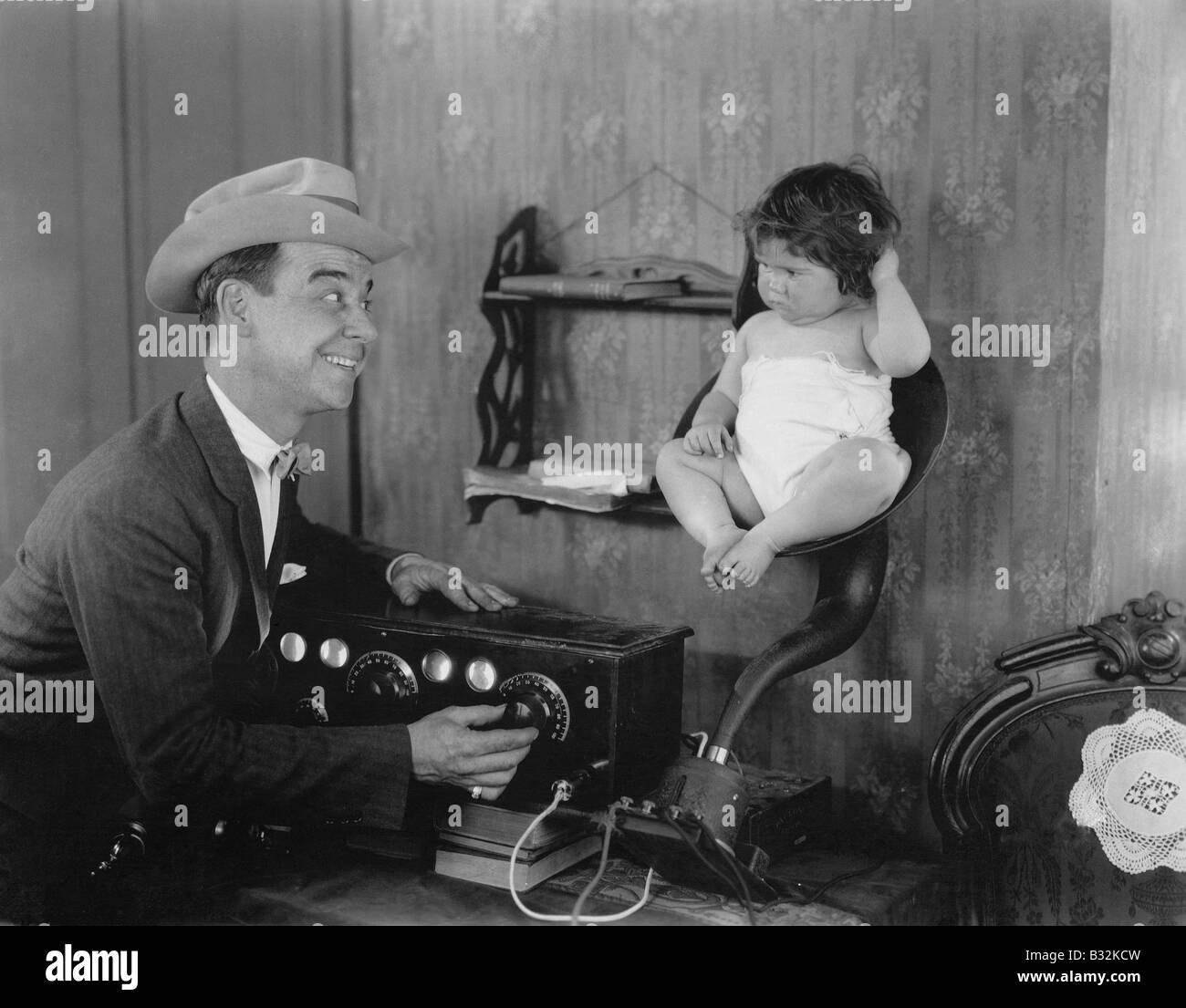 Father with baby in speaker horn of old radio Stock Photo