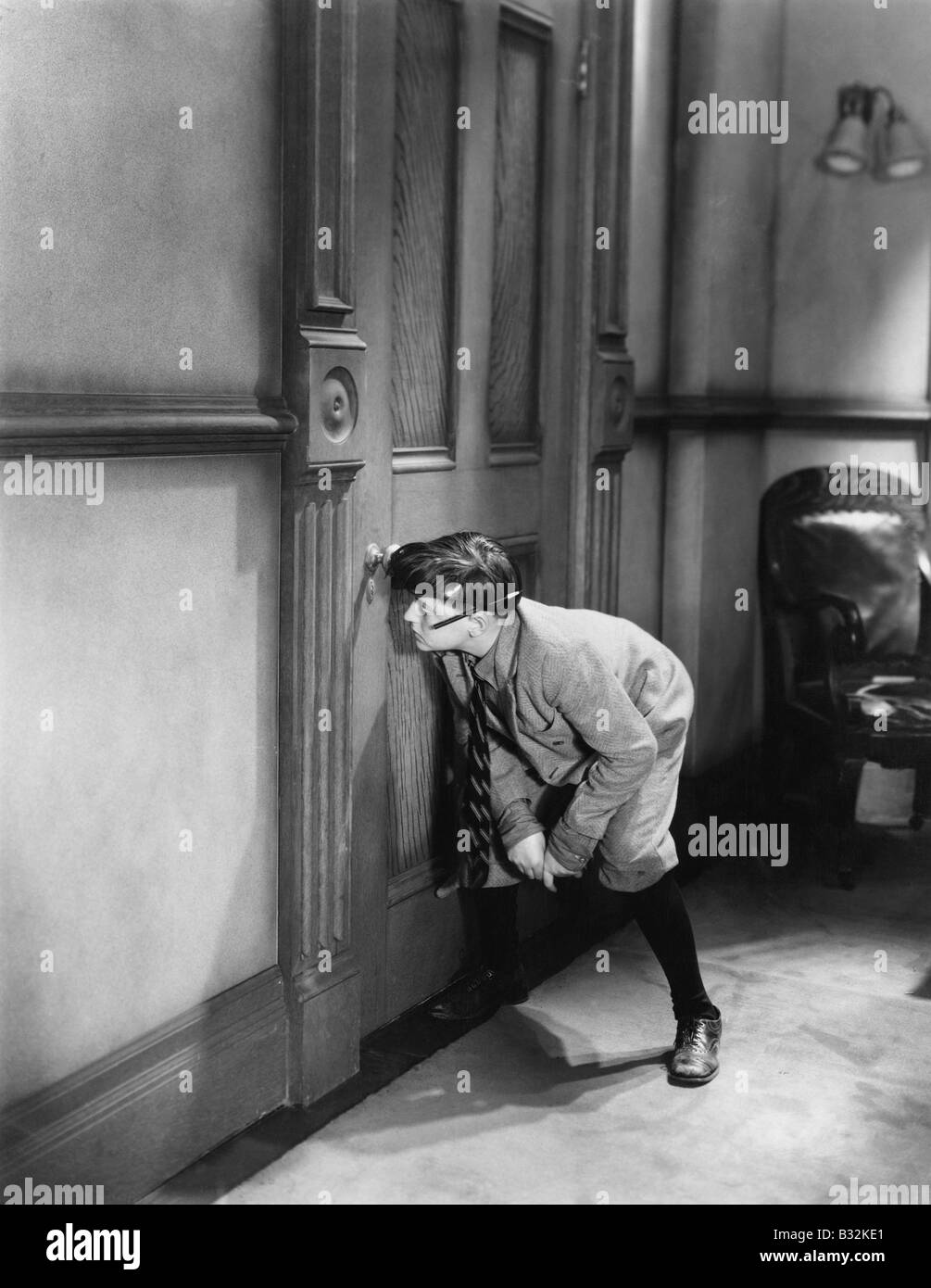 Teenage boy peeping through keyhole Stock Photo - Alamy