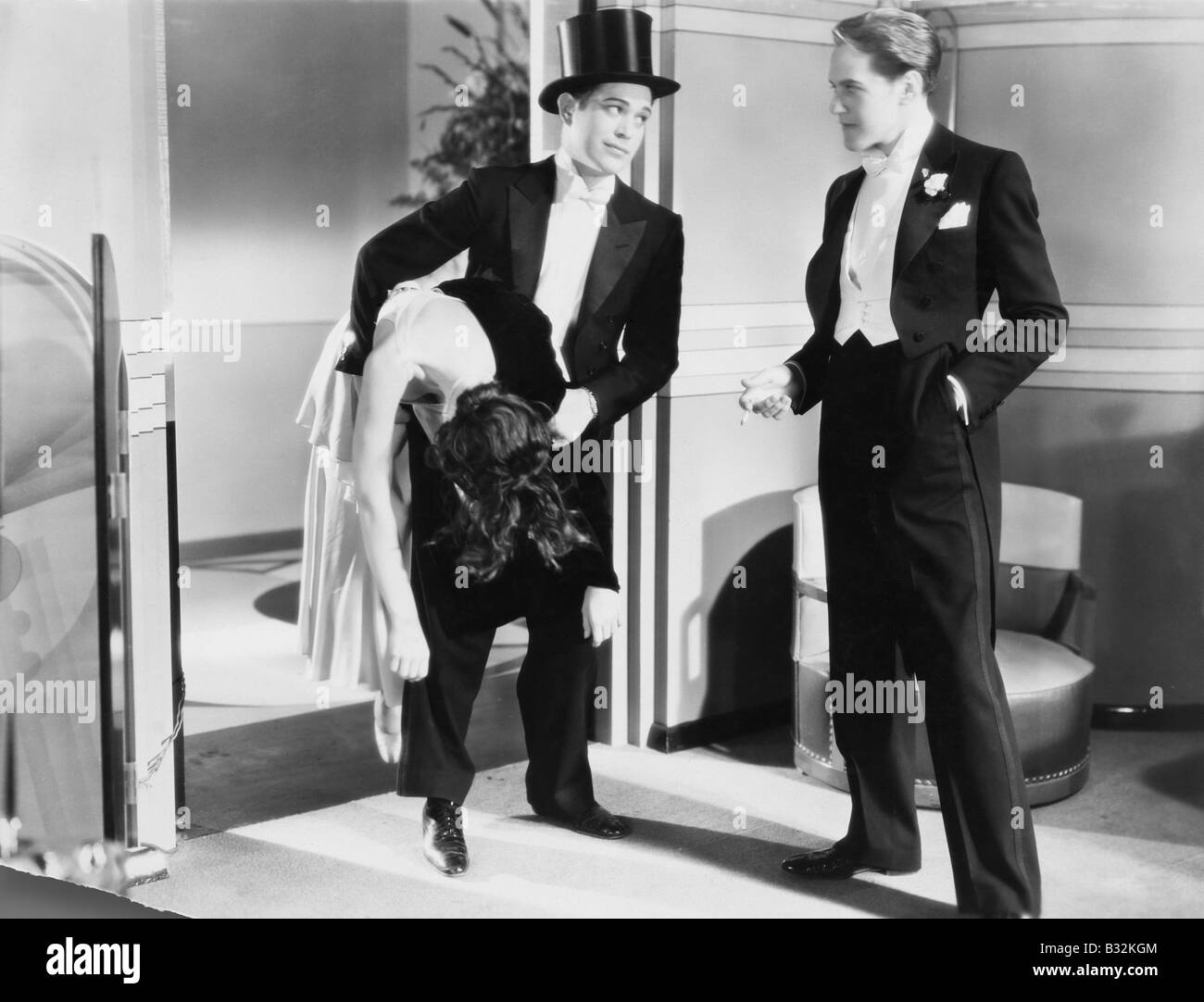 Two men in tuxedos with unconscious woman Stock Photo - Alamy