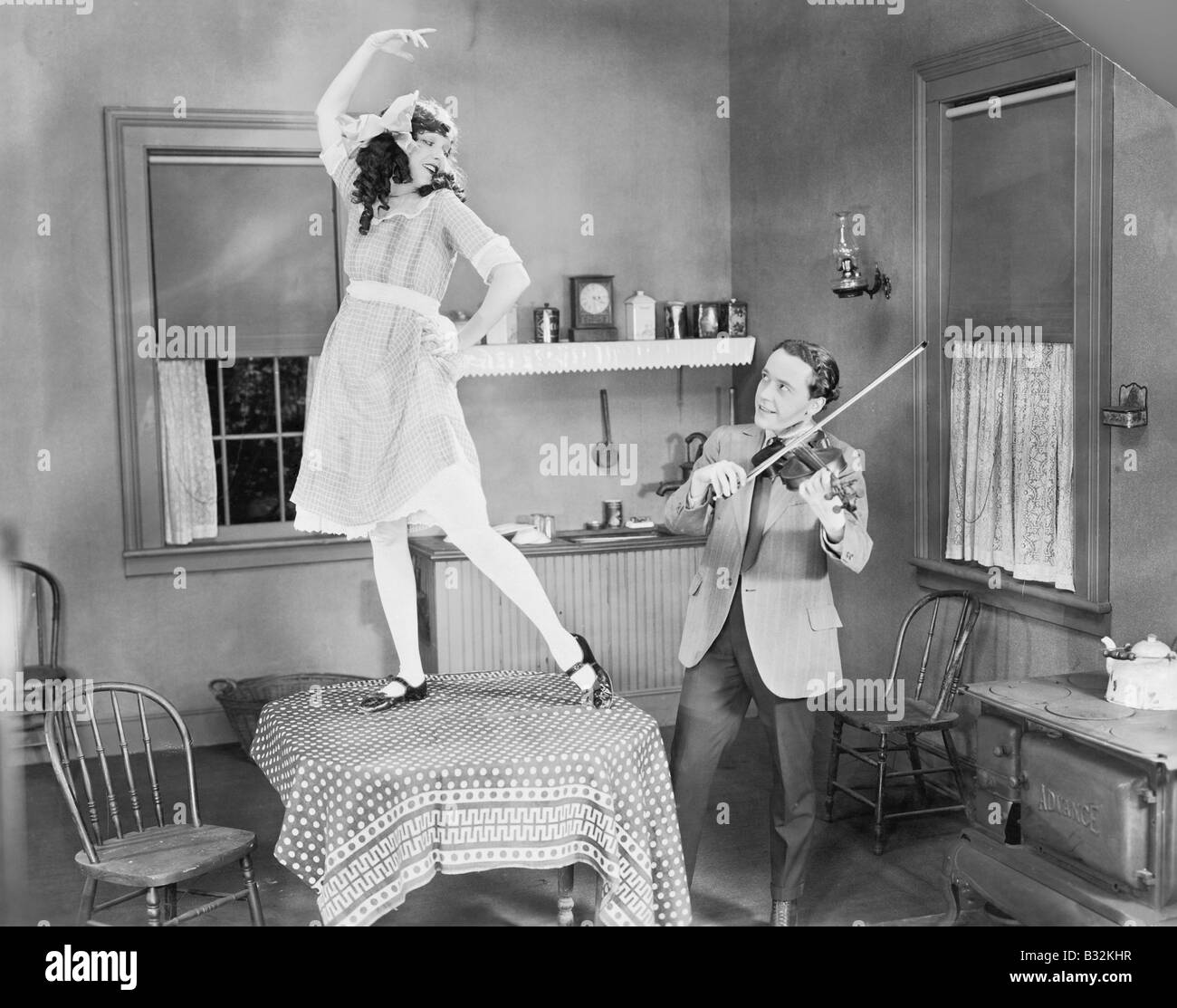 Man playing violin for woman dancing on table Stock Photo