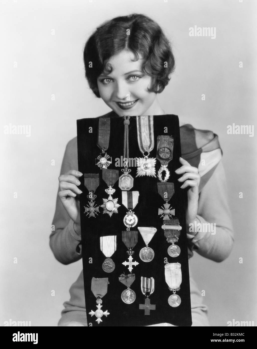 Woman holding display of medals Stock Photo