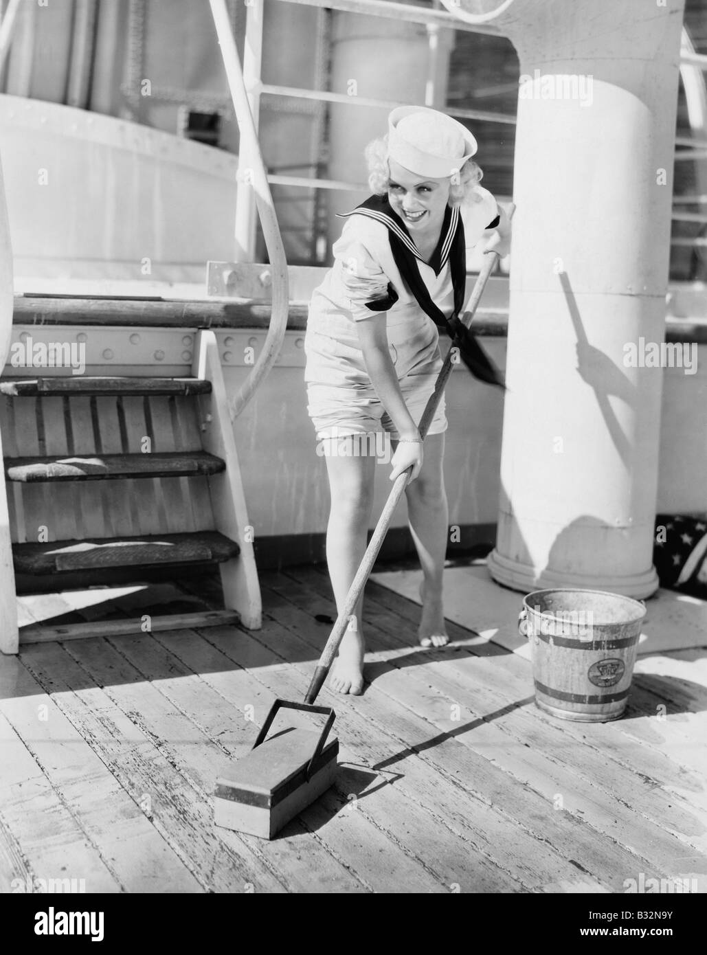 Female sailor swabbing boat deck Stock Photo