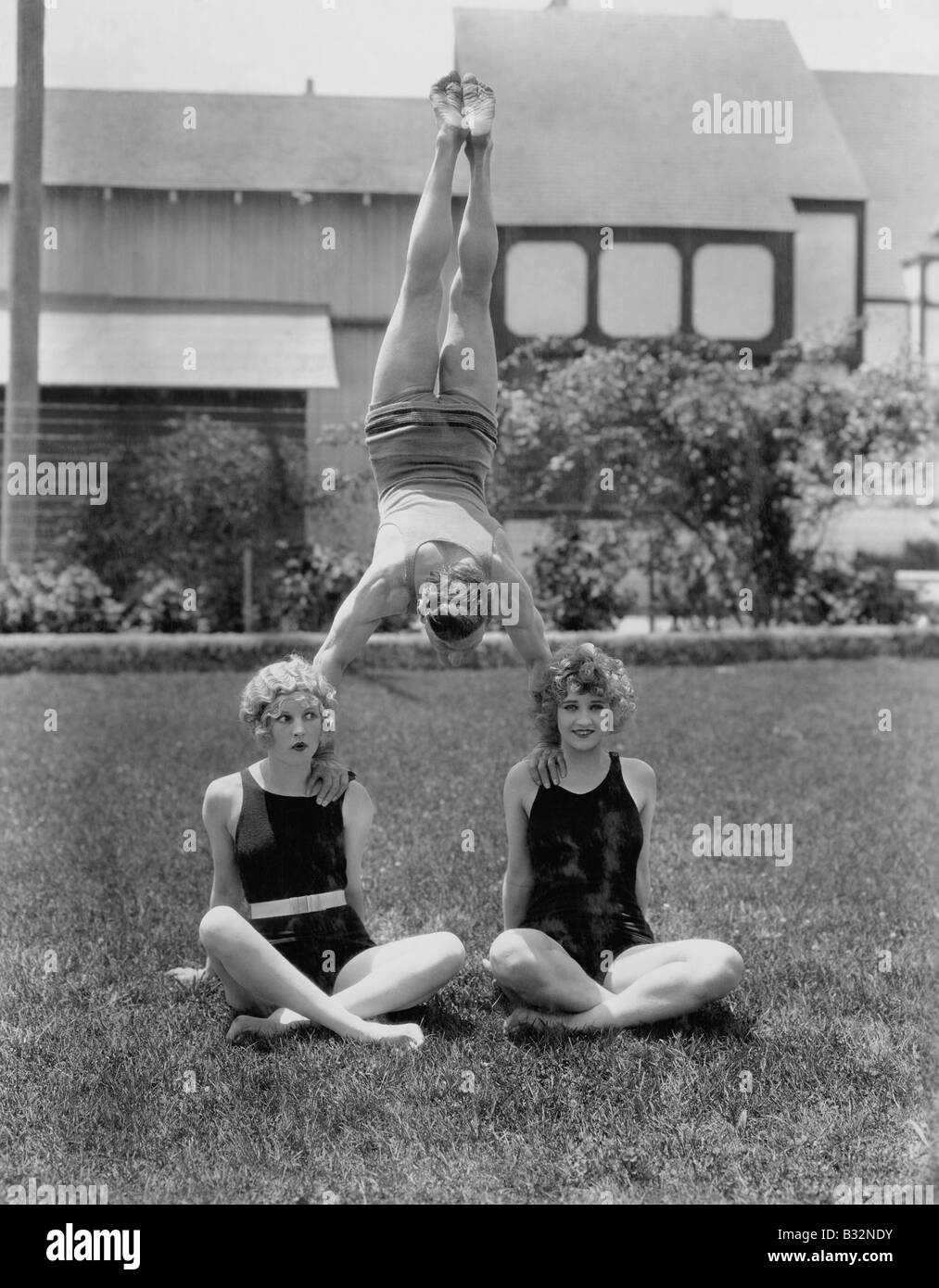 Acrobat balancing on womens shoulders Stock Photo