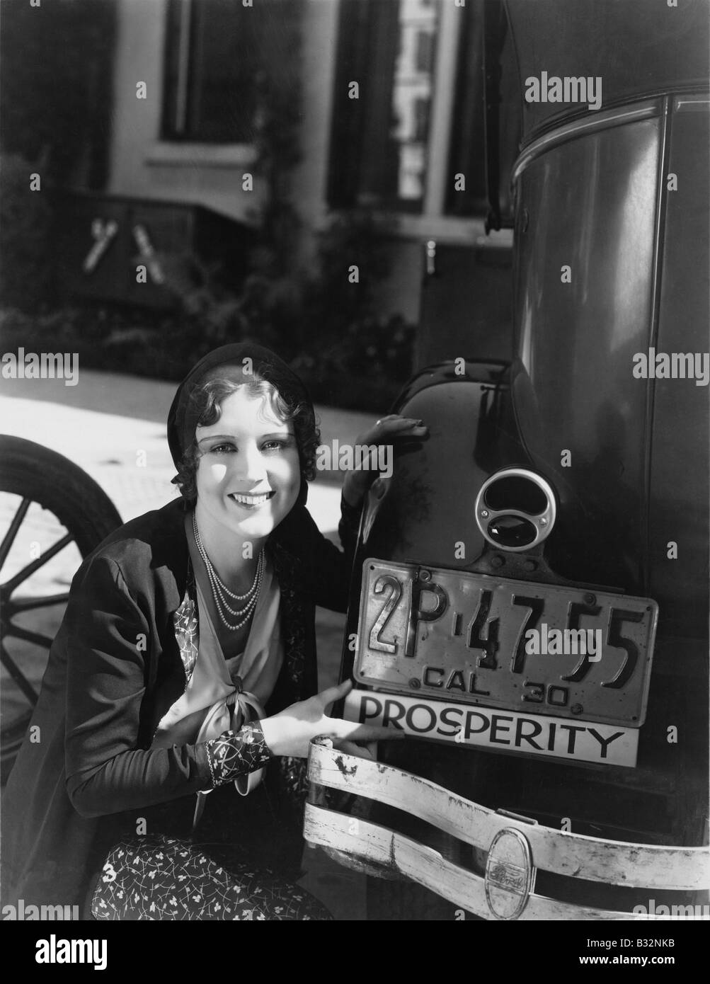 Woman with prosperity sign on car bumper Stock Photo