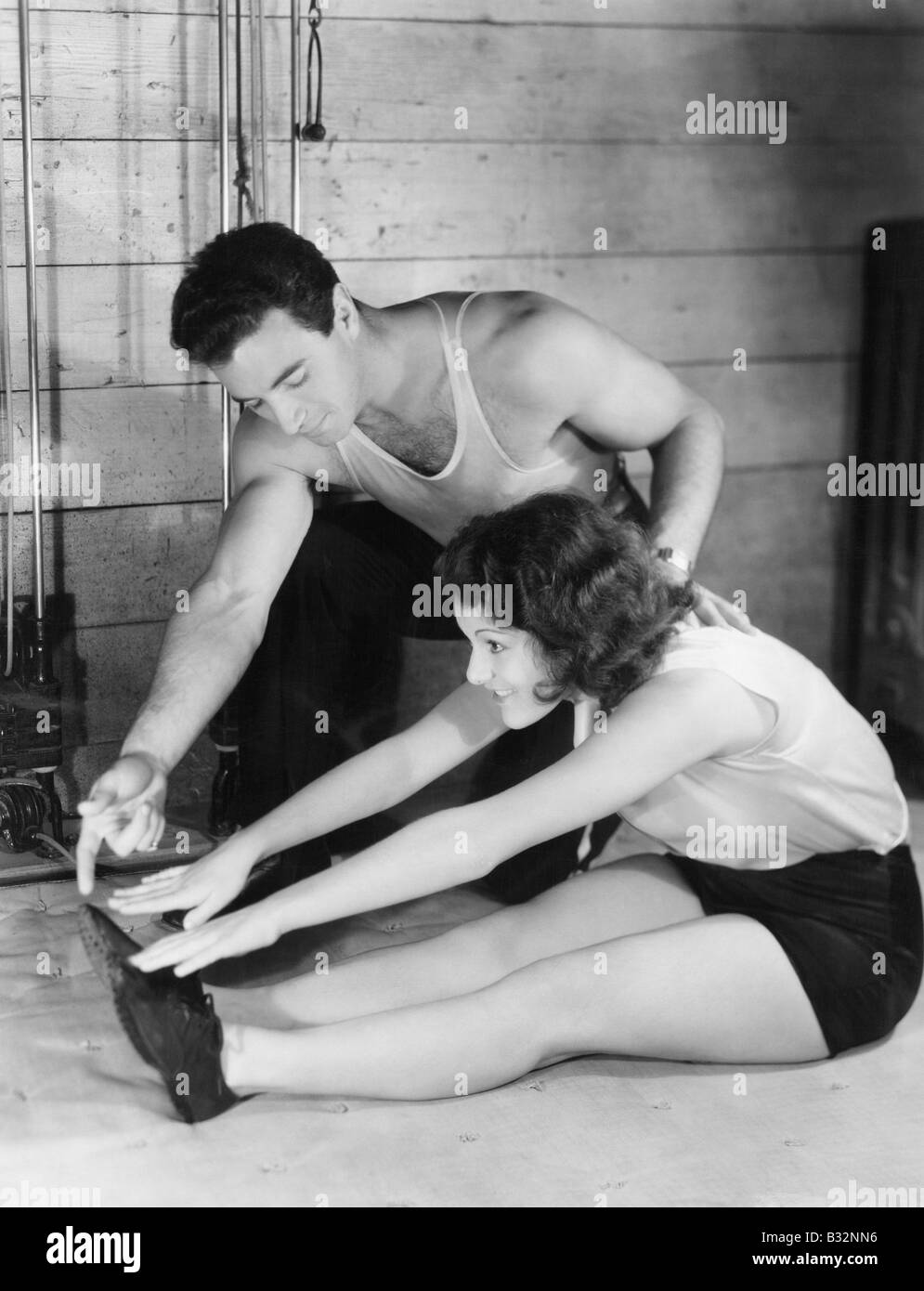 Woman stretching with help from trainer Stock Photo