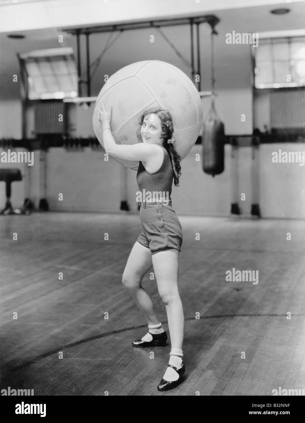 Woman in gymnasium with huge ball Stock Photo