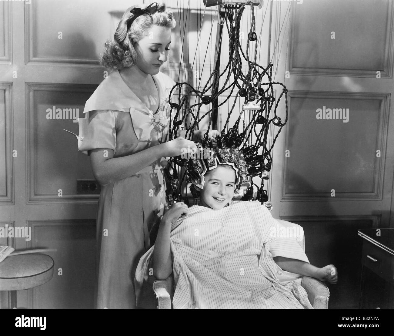 Woman using machine to style teenage girls hair Stock Photo