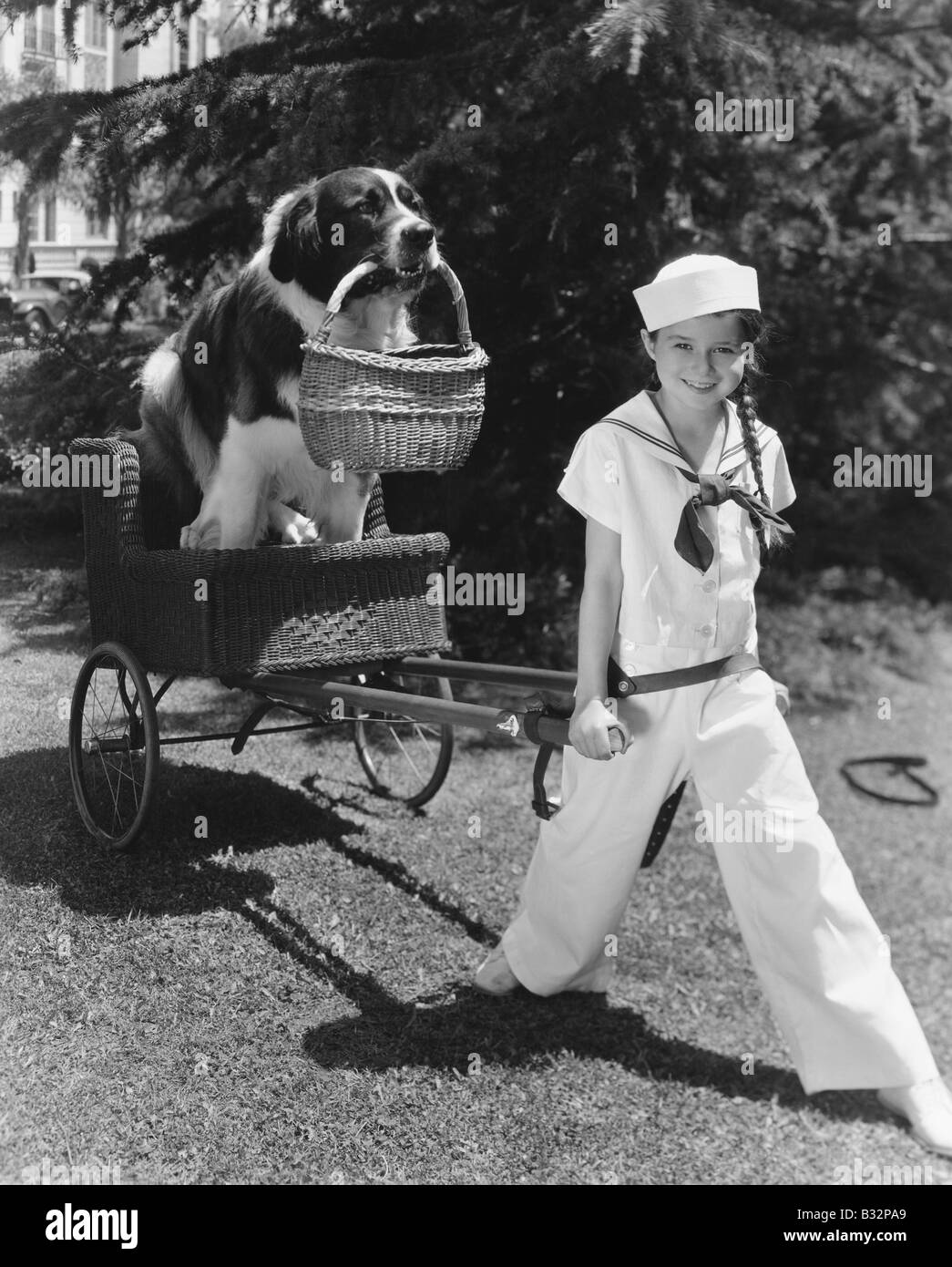 Girl in sailor suit pulling dog in basket Stock Photo