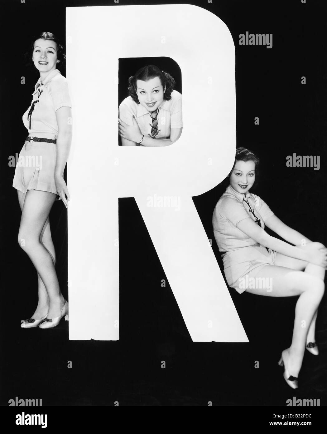 Three women posing with huge letter R Stock Photo